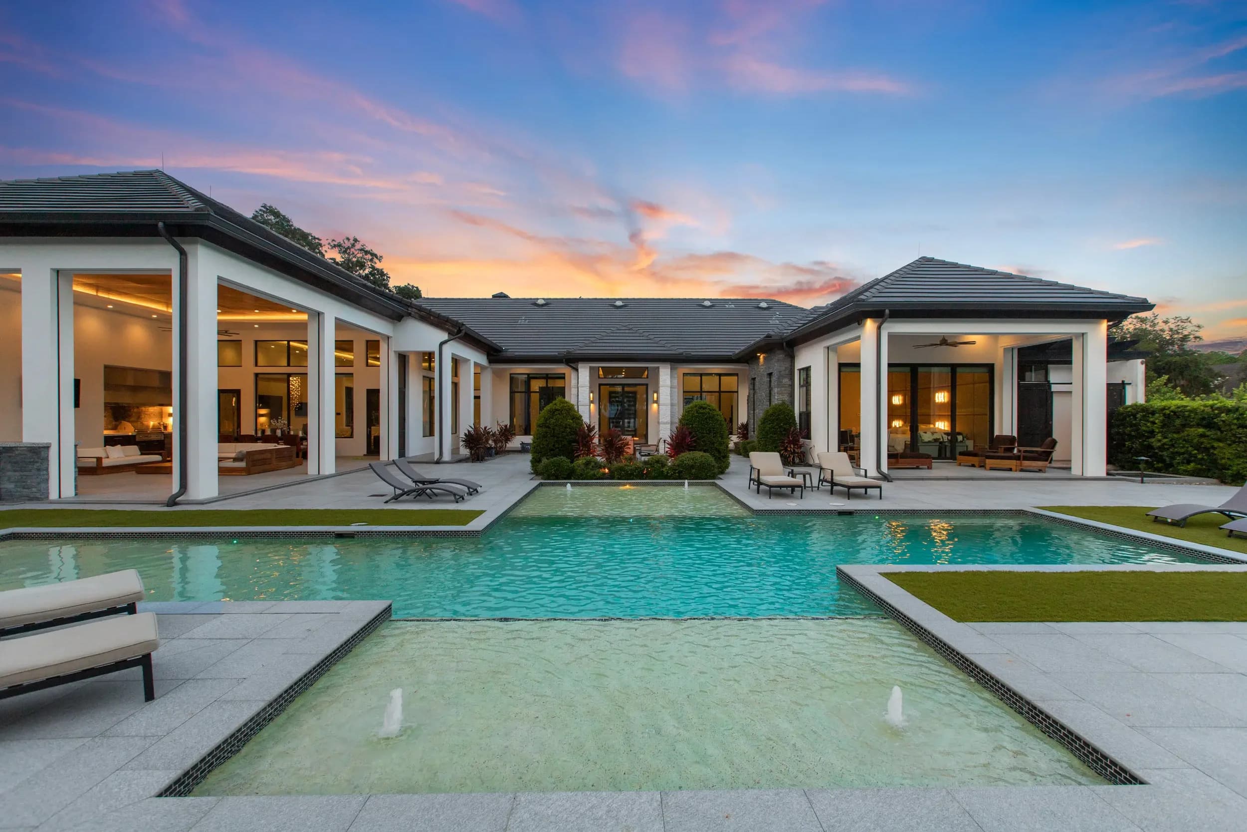 Aerial of a modern home wrapped around a courtyard pool at sunset