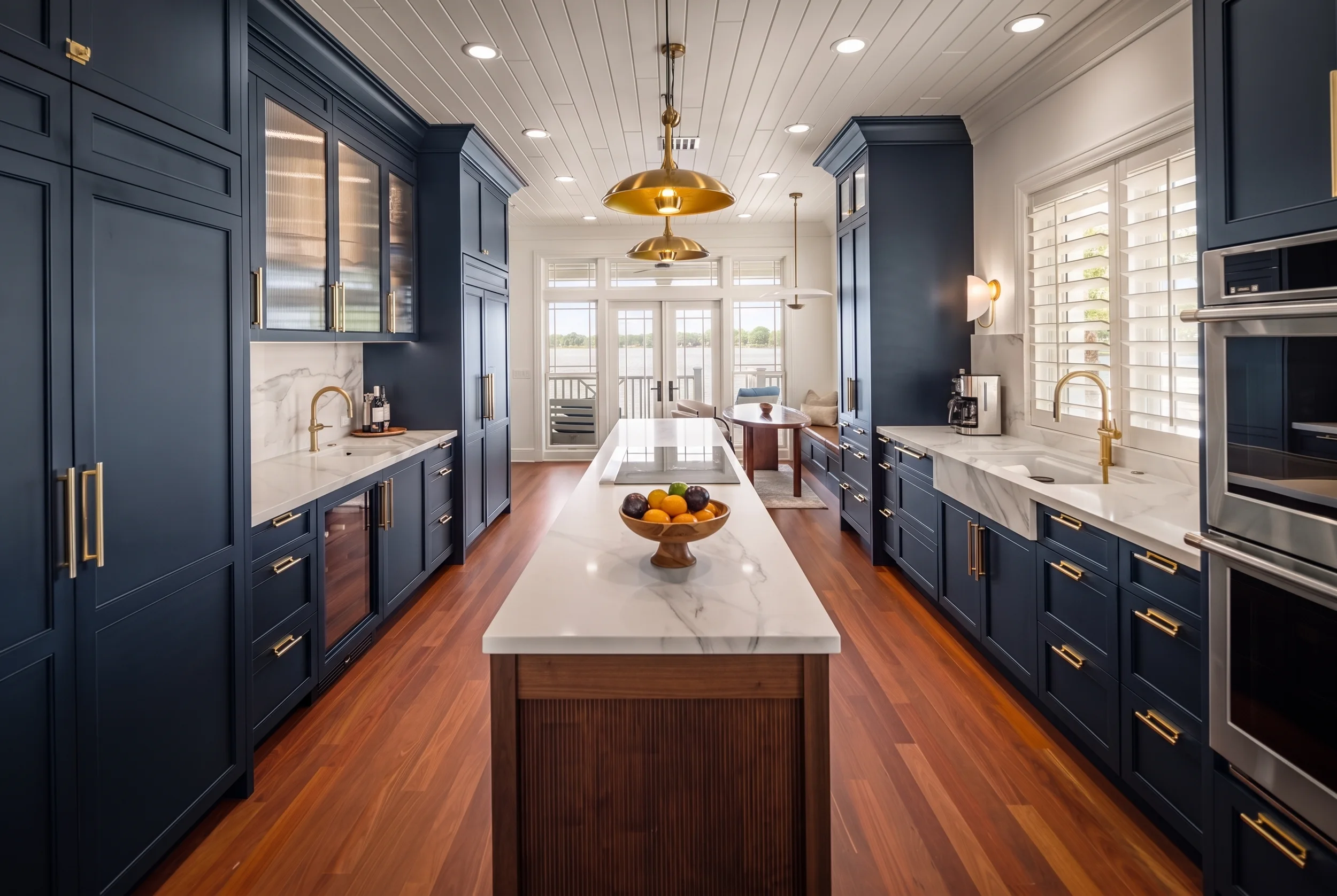 Navy galley kitchen with a marble island, brass hardware, shiplap ceiling, and a brass dome pendant