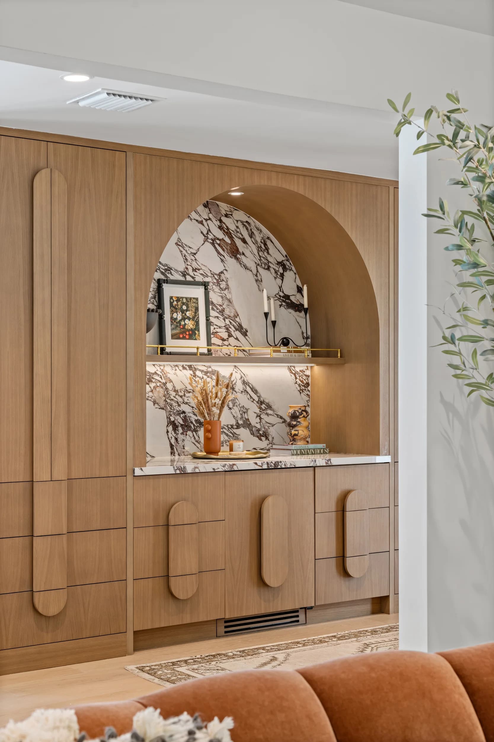 Custom white oak bar cabinetry with a book-matched marble arch niche