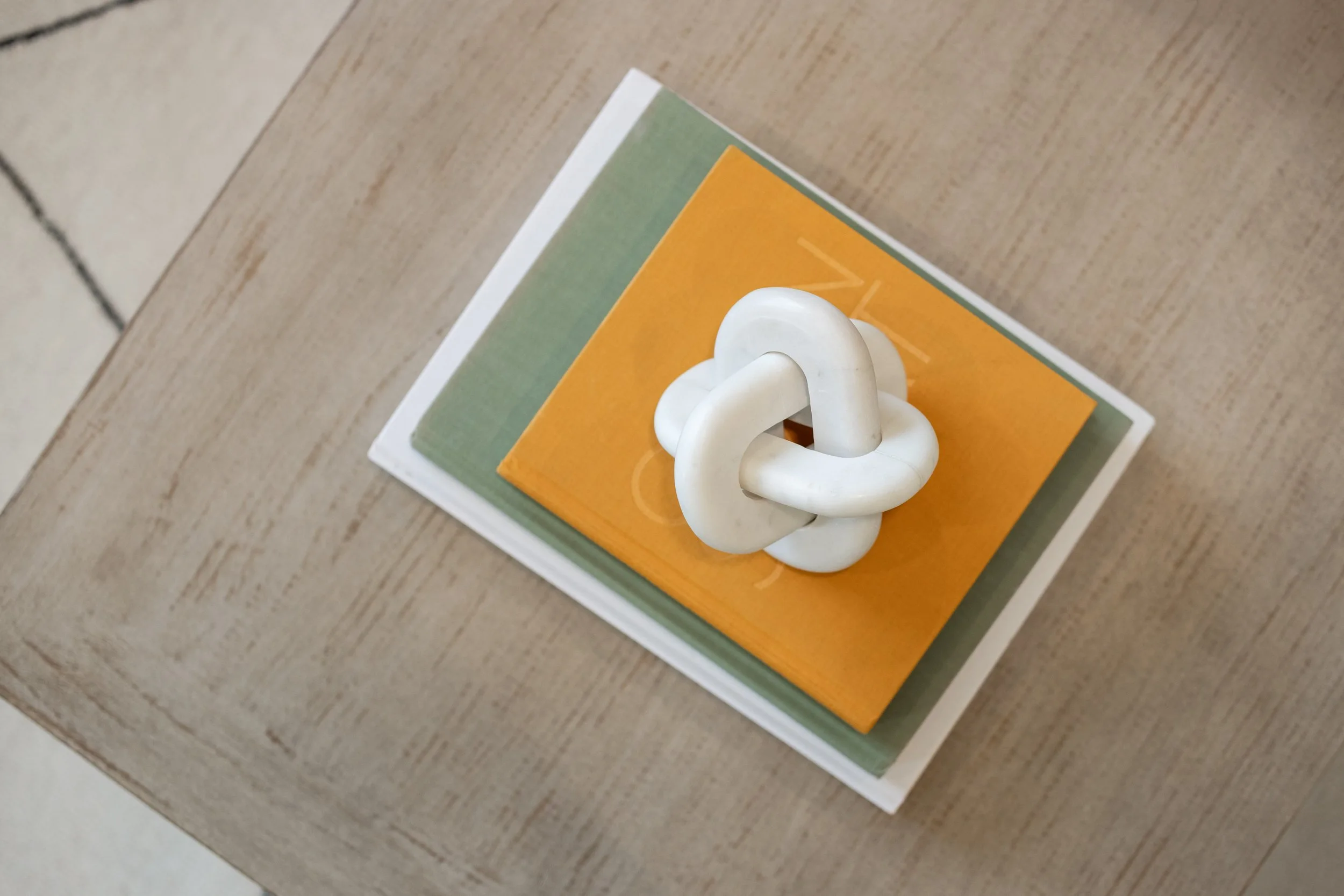 Coffee table detail with a ceramic knot sculpture on stacked books
