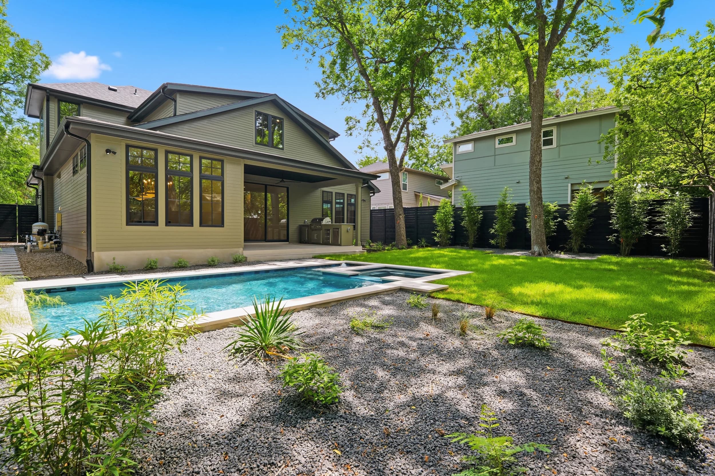 Backyard with a pool and spa, covered patio and native landscaping