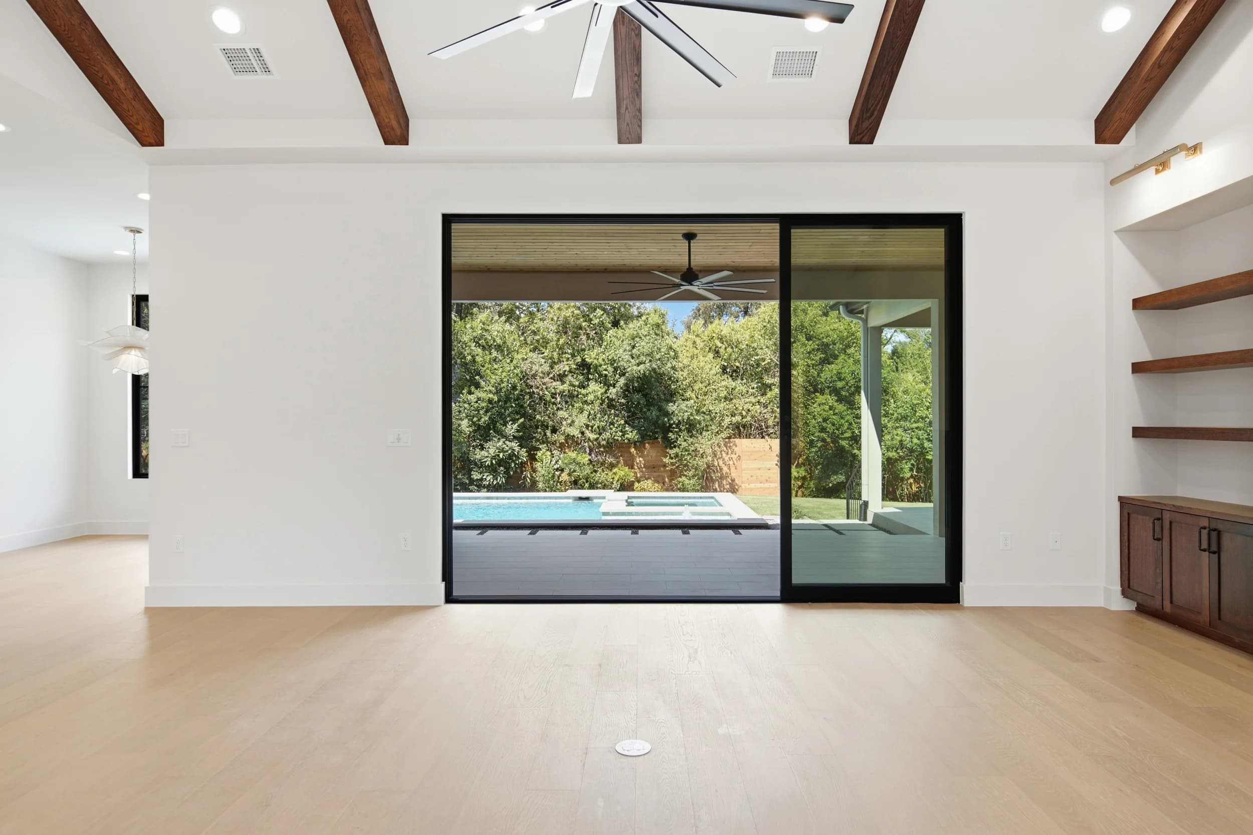 Great room with exposed wood beams and sliding glass doors to a covered patio and pool