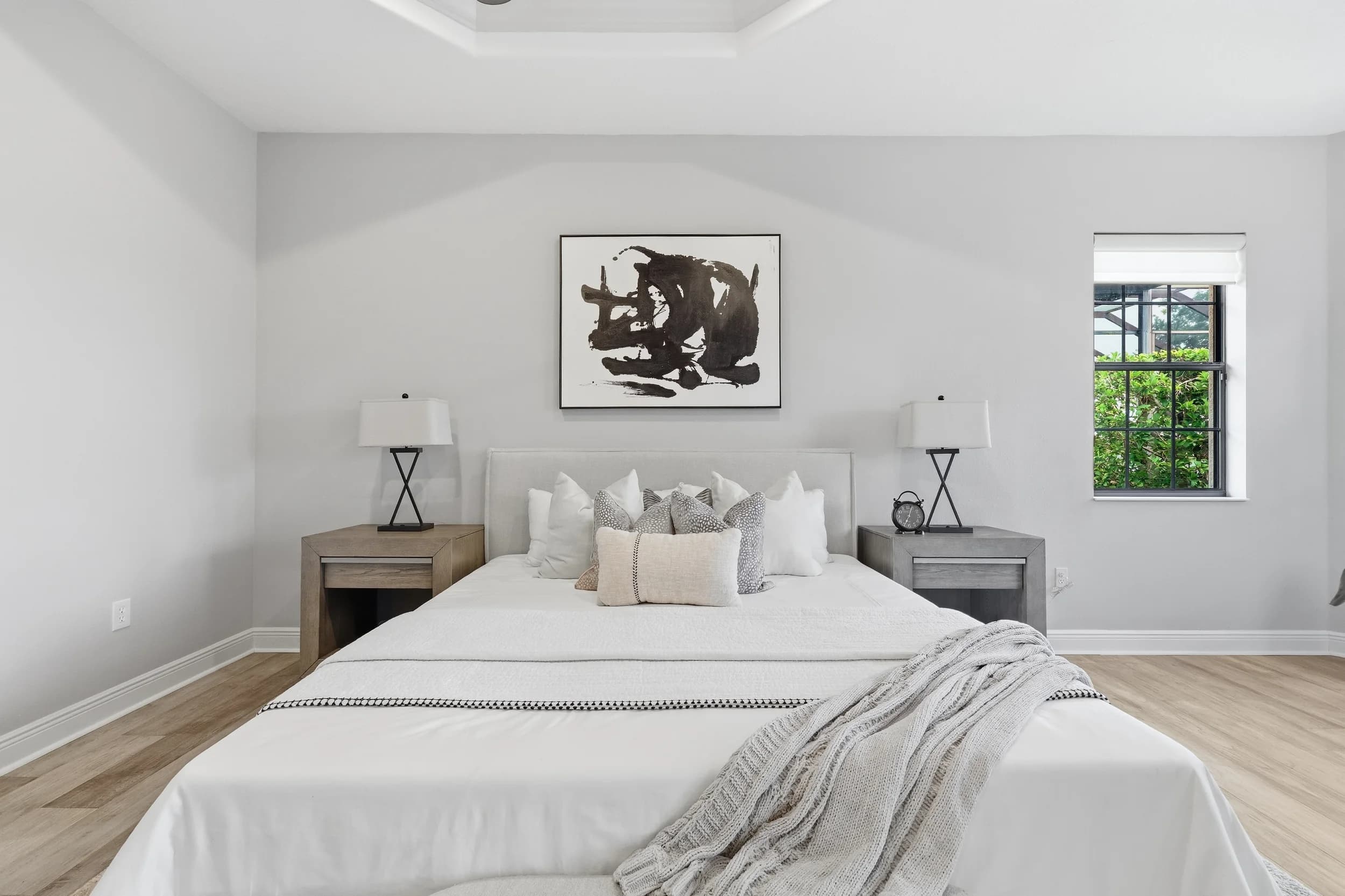 Primary bedroom with white bedding, black-framed art and matching nightstand lamps