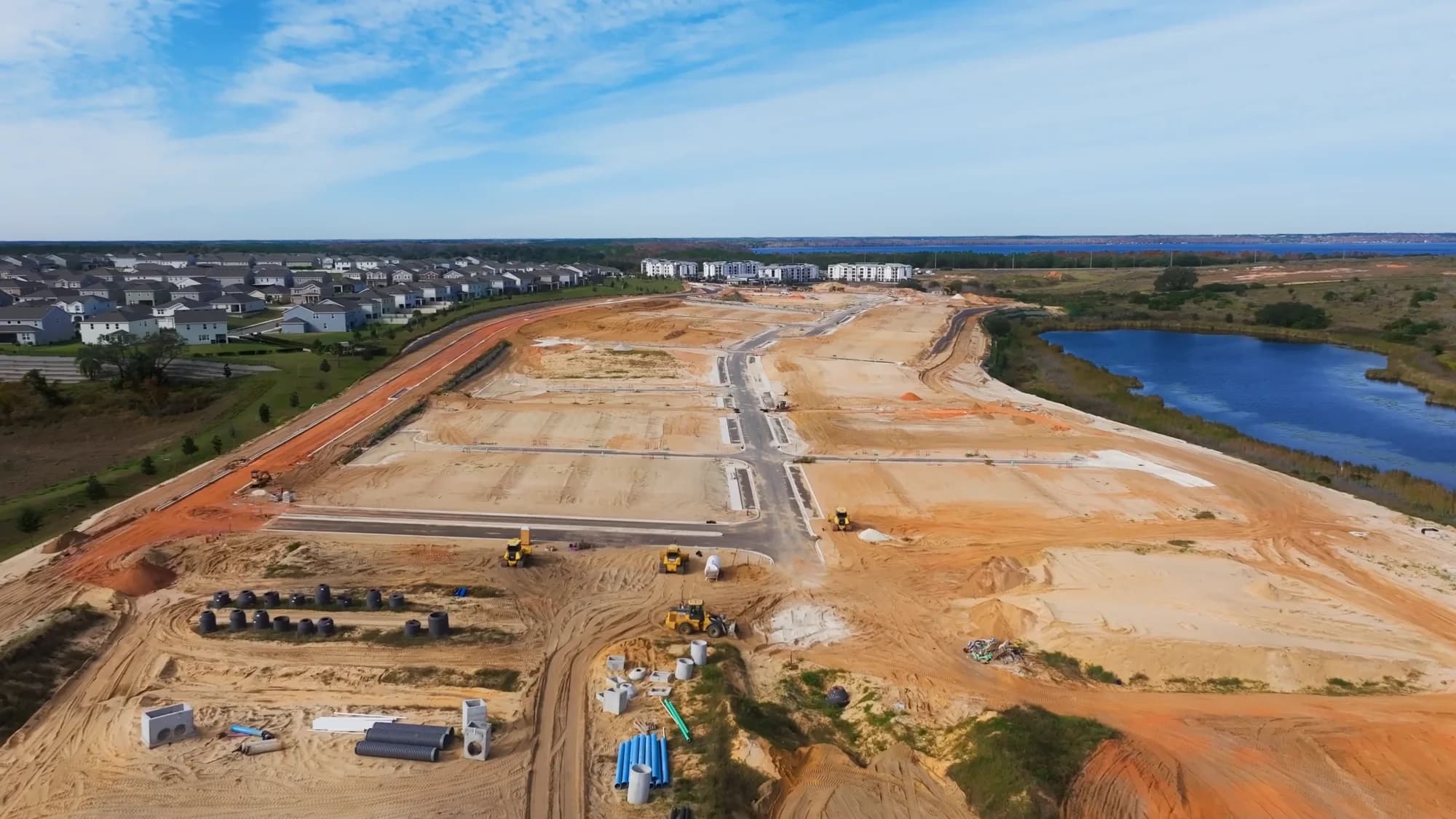 Aerial of an active construction site with lots being graded, roads cut in, and utilities staged