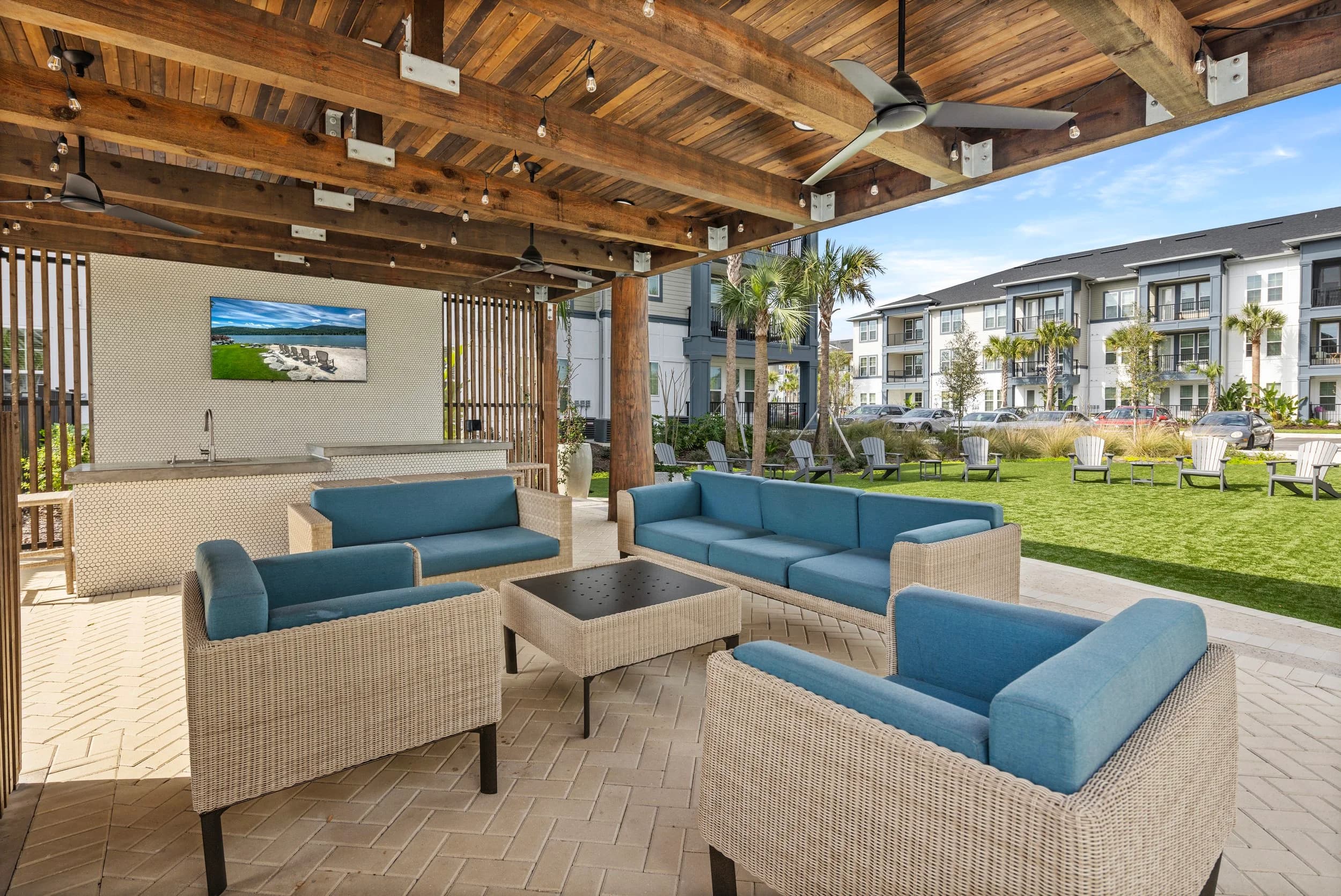 Covered outdoor lounge with blue sofas and a TV