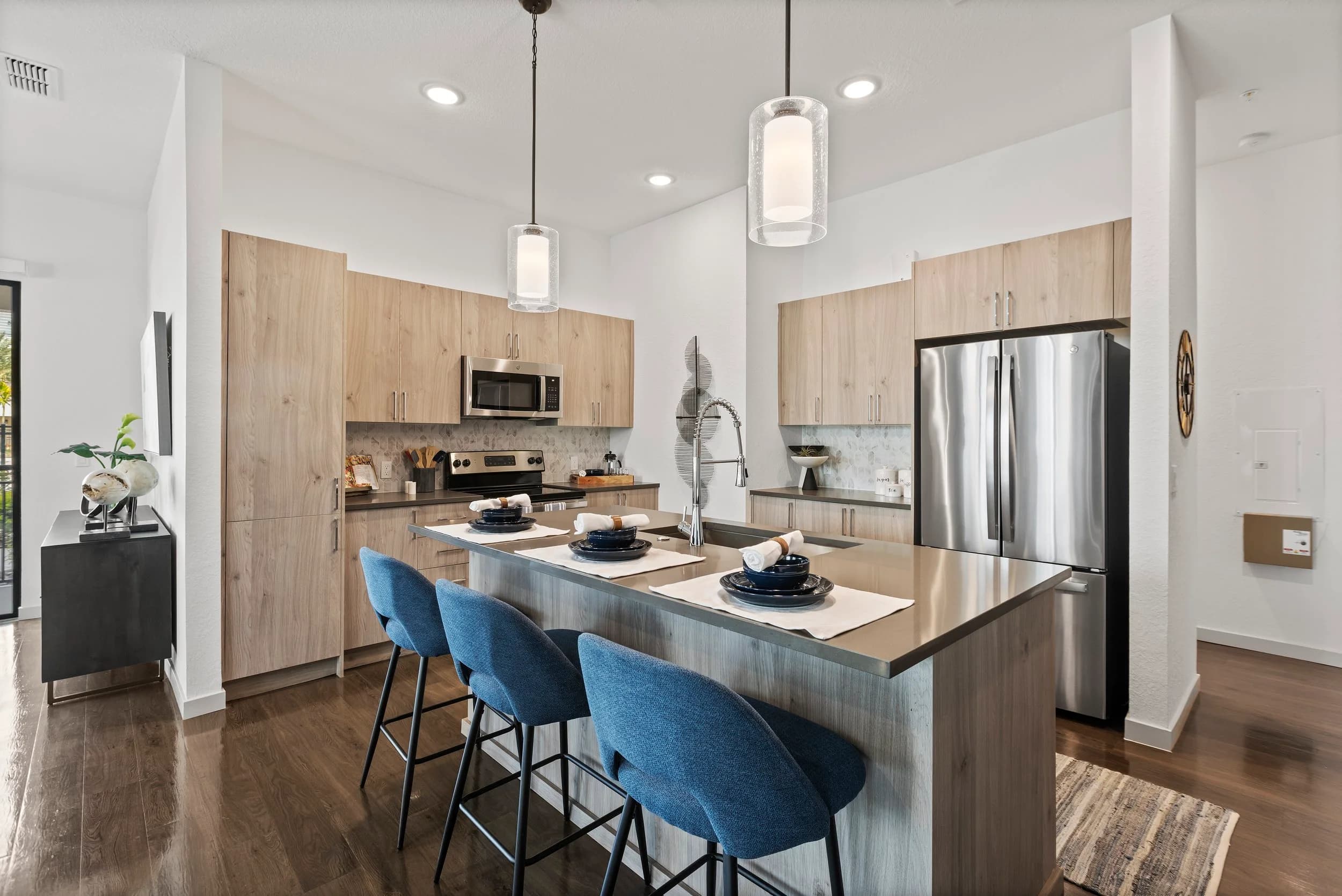 Apartment kitchen with blue stools and wood cabinets