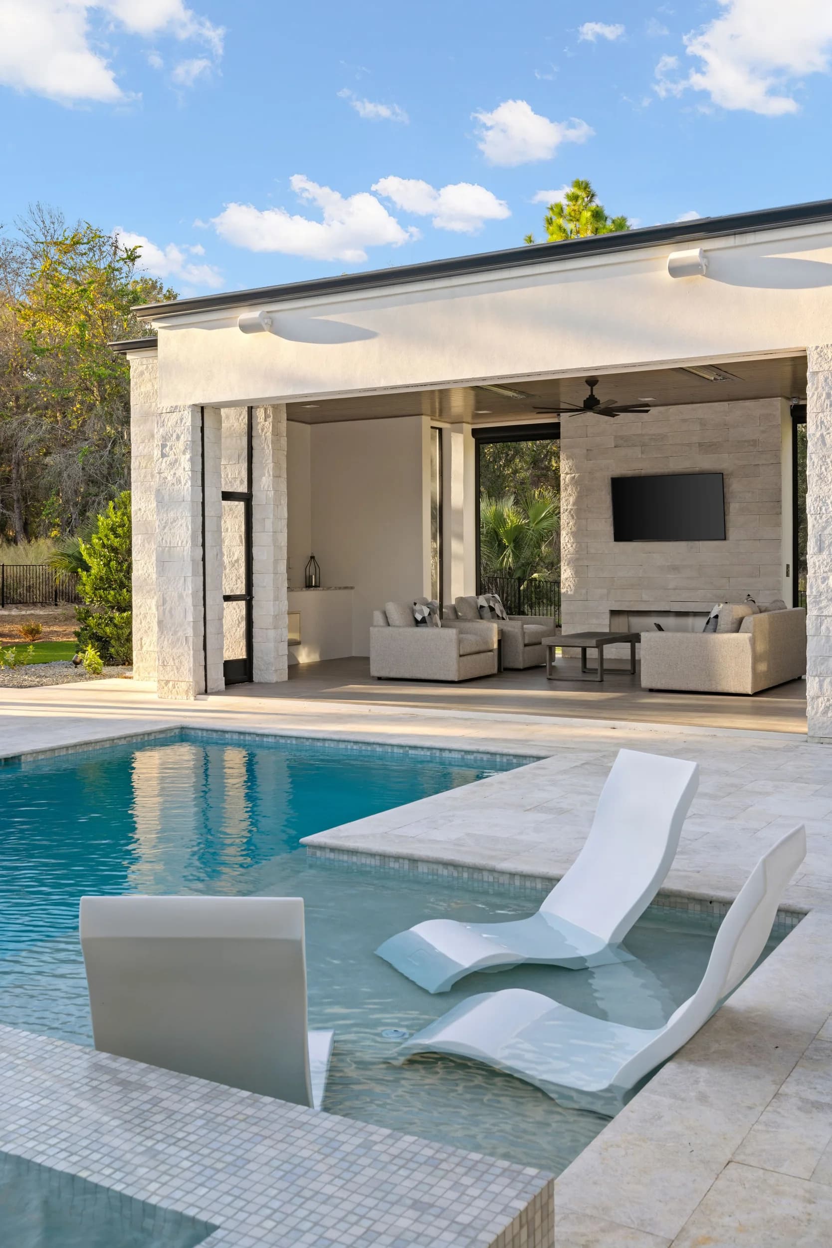 Covered lanai with outdoor living room opening to a pool