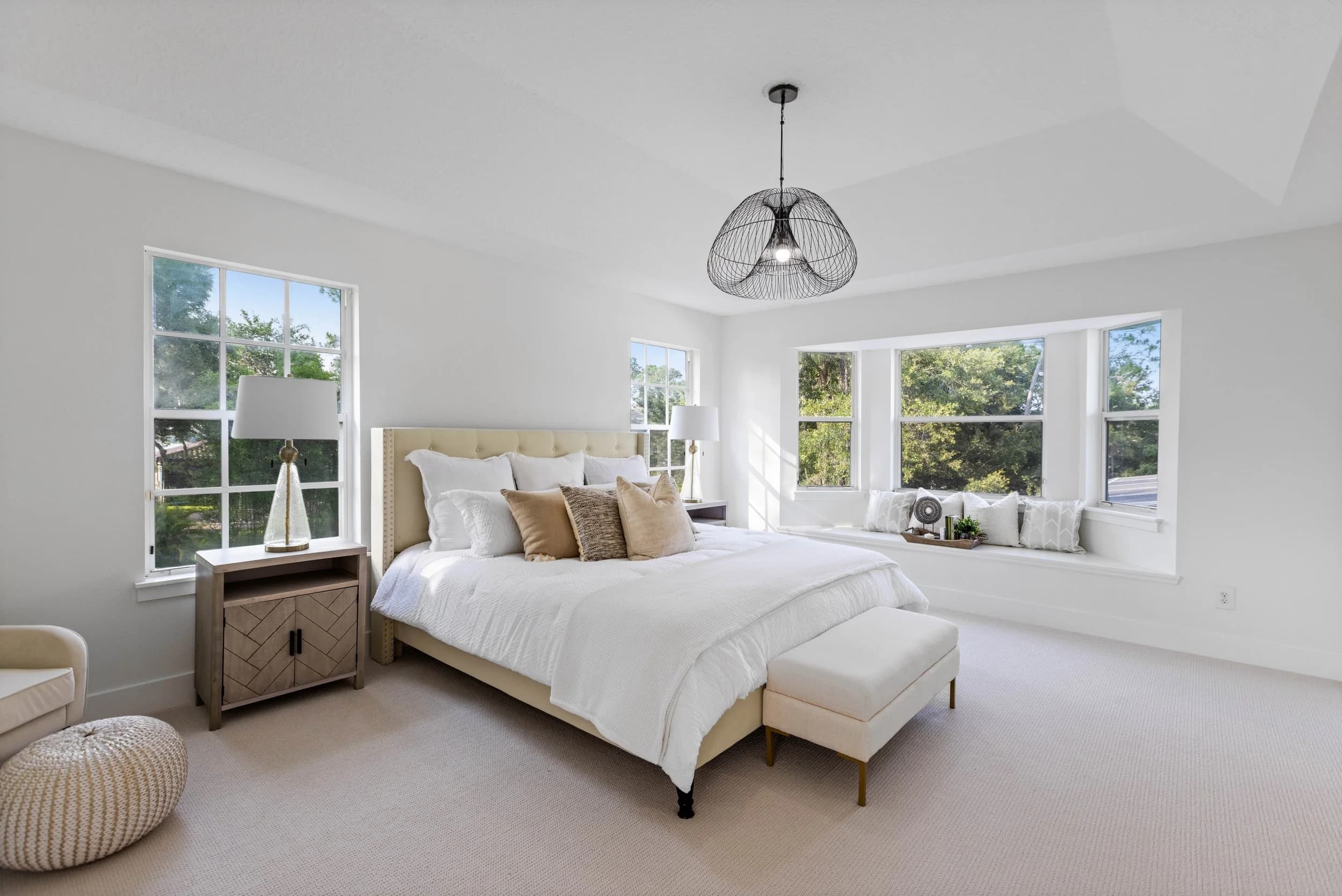 Bright primary bedroom with bay windows and white bedding