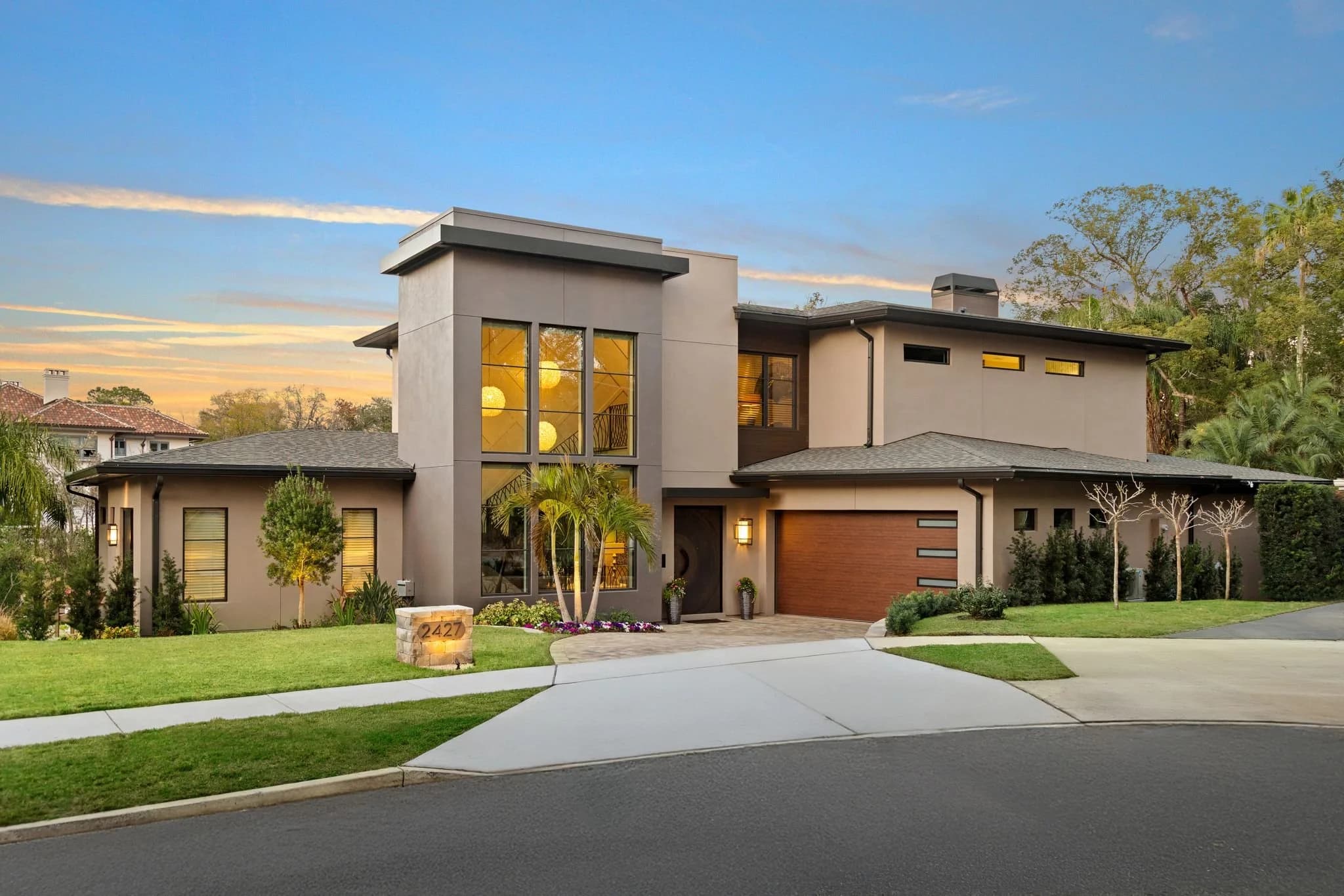 Modern two-story home at dusk with landscaped front yard