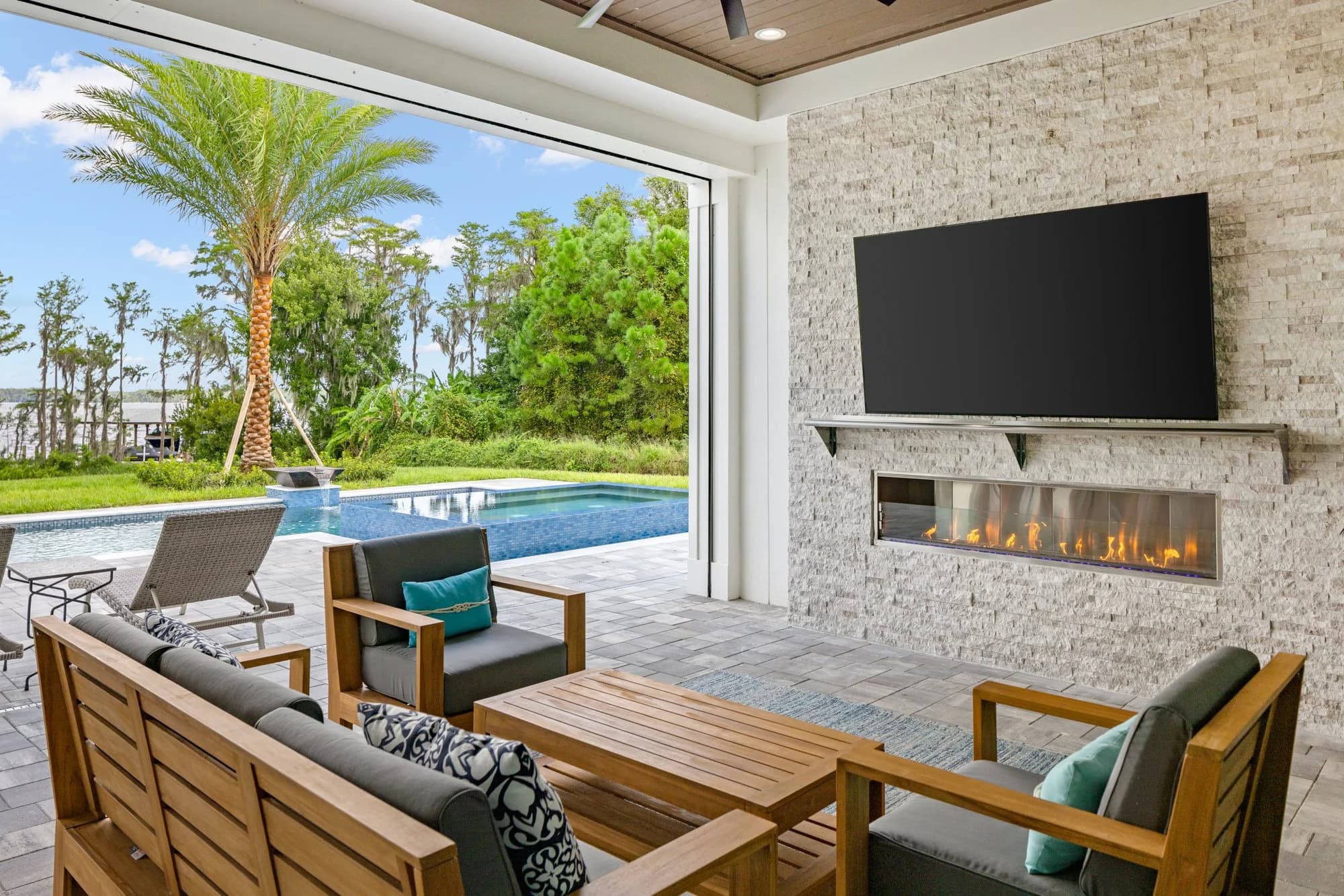 Covered lanai with outdoor kitchen, fireplace, and pool view