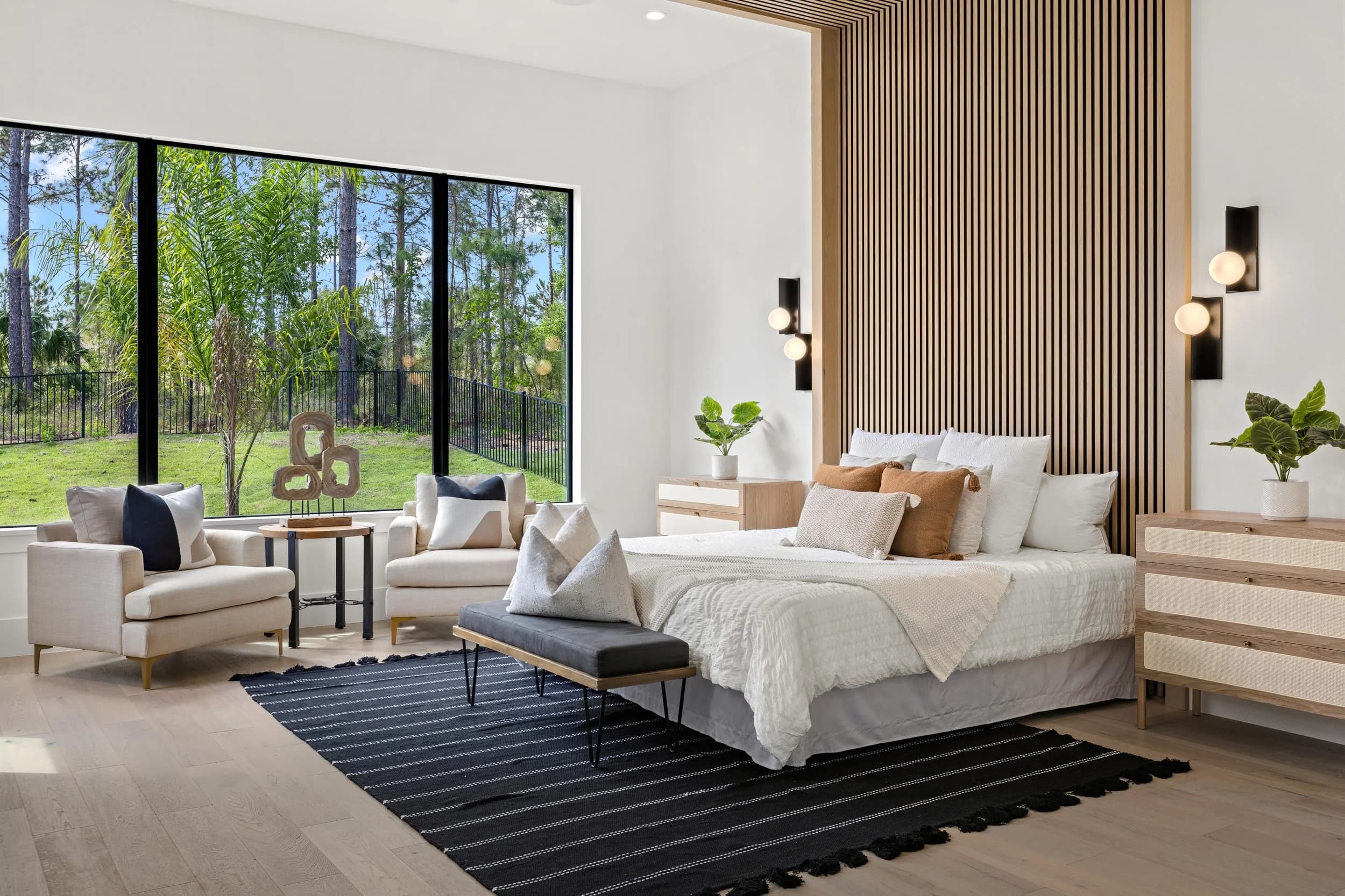 Model primary bedroom with wood slat wall and glass doors