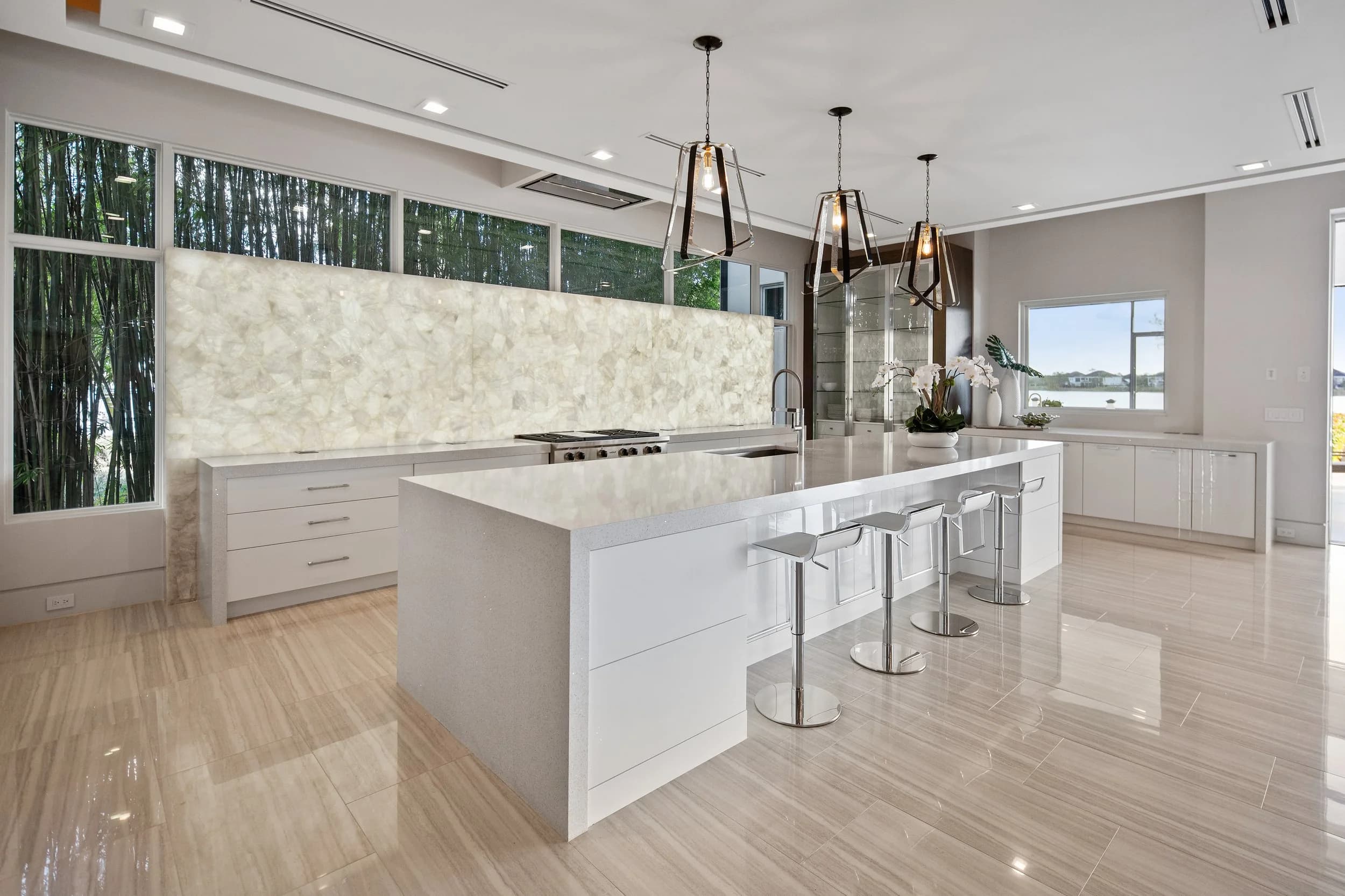 White kitchen with marble waterfall island and brass pendants