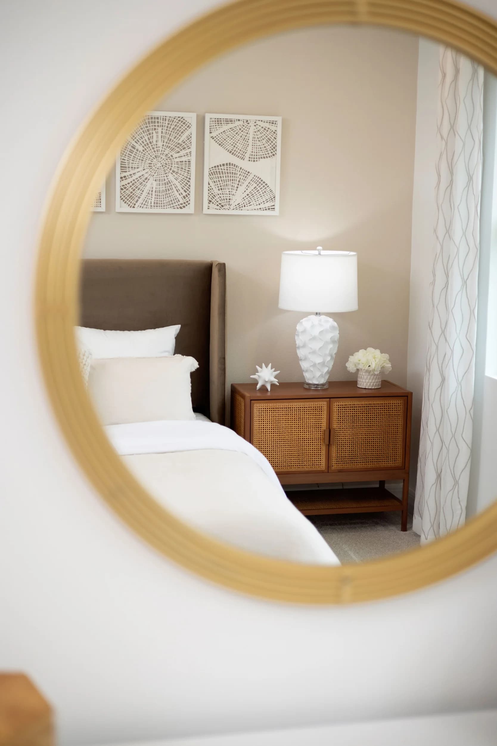 Bedroom detail with upholstered headboard, rattan nightstand, and white lamp