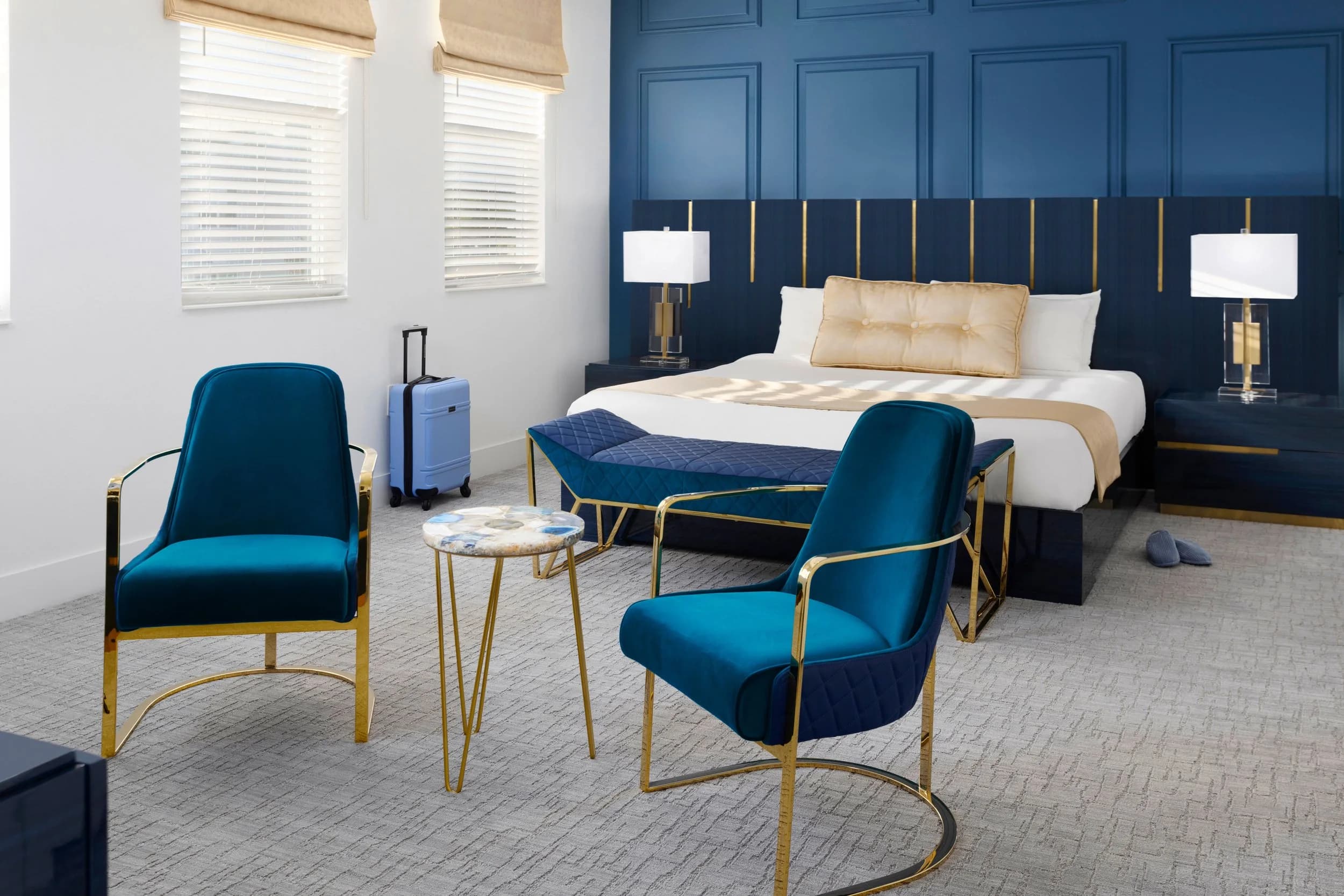 Primary bedroom with navy paneled wall, brass sconces, and velvet chairs