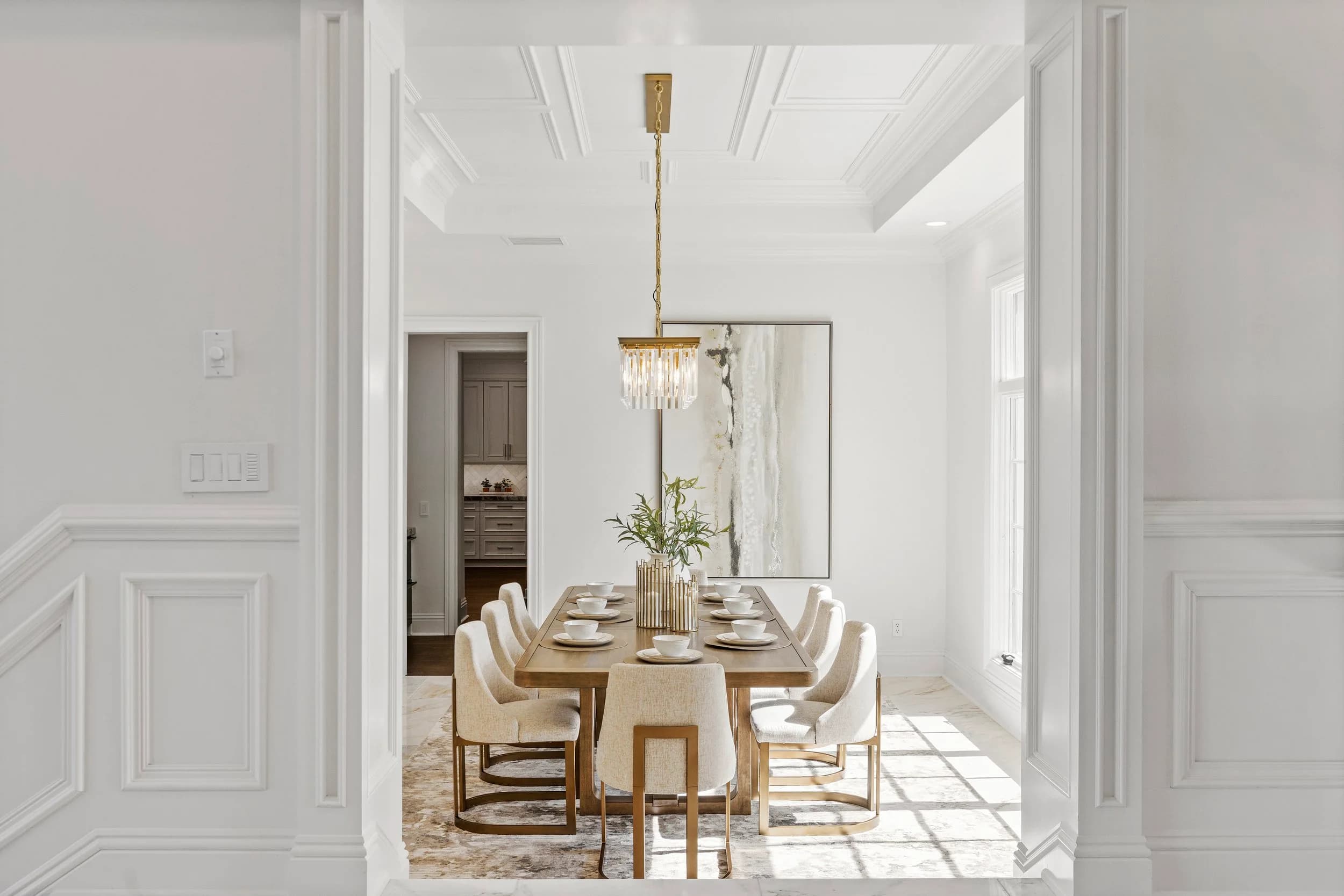 White dining room with crystal chandelier and coffered ceiling