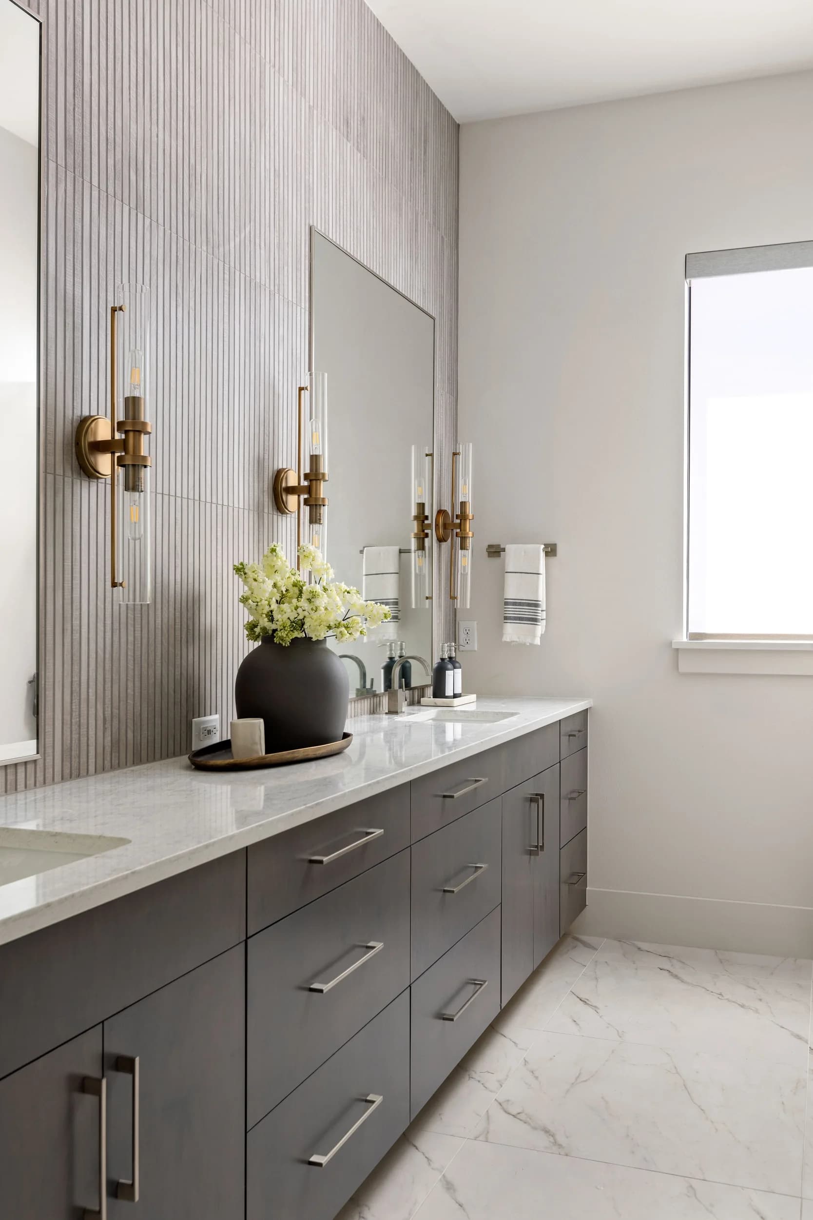Vanity detail with black sconces, brass mirror, and styled florals