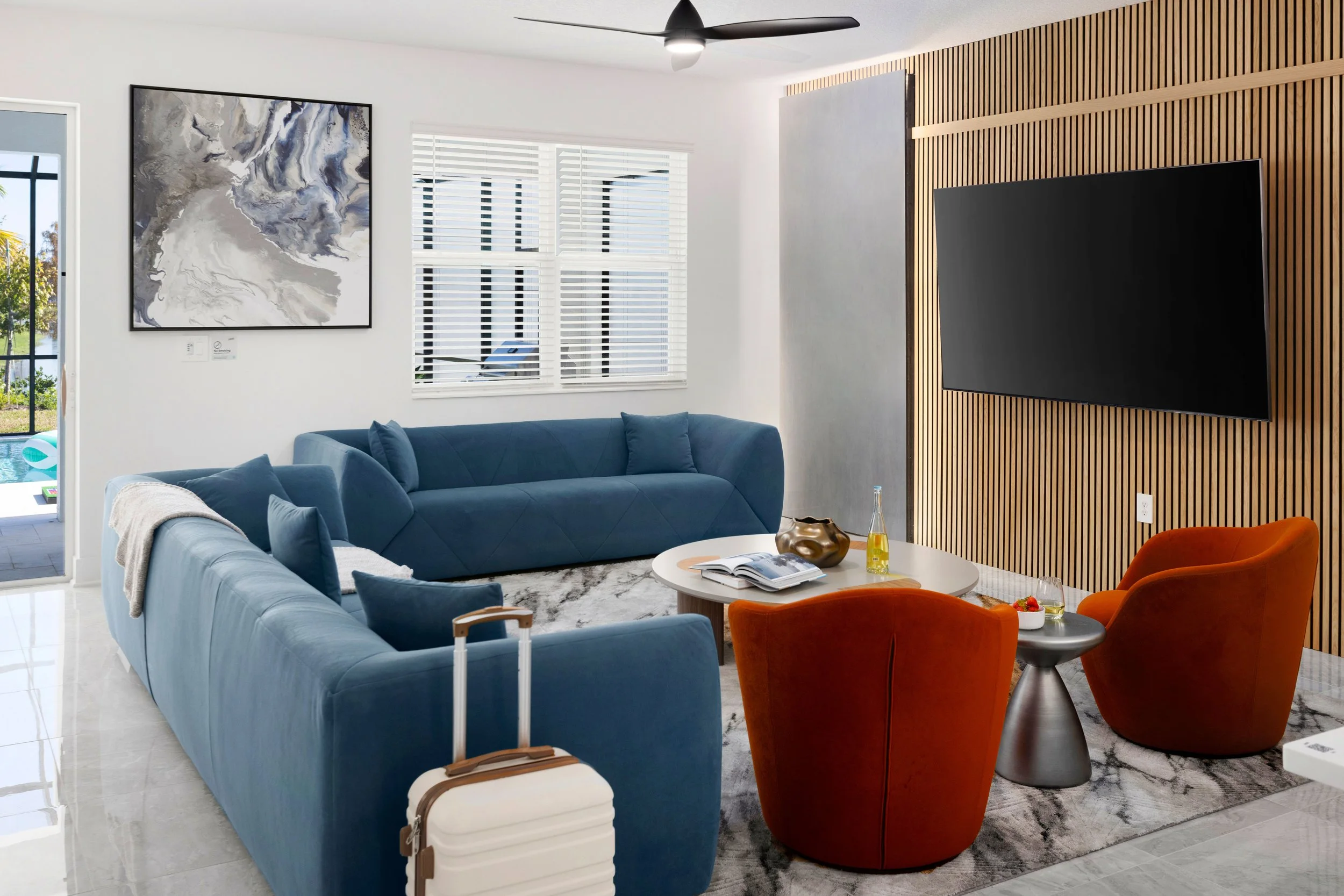 Living room with blue sectional, slatted wall, and orange accents