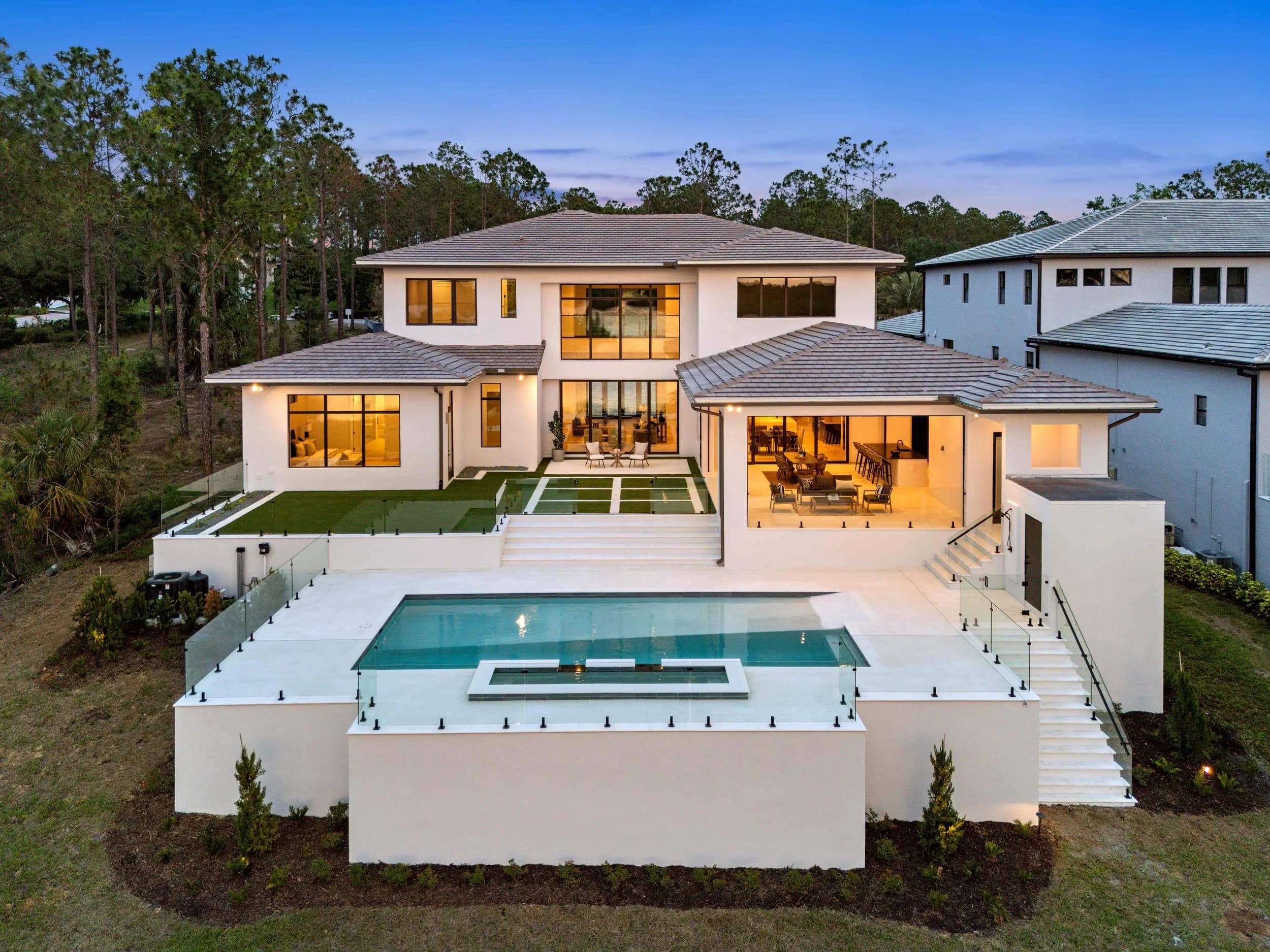 Two-story model home at twilight with pool and covered lanai