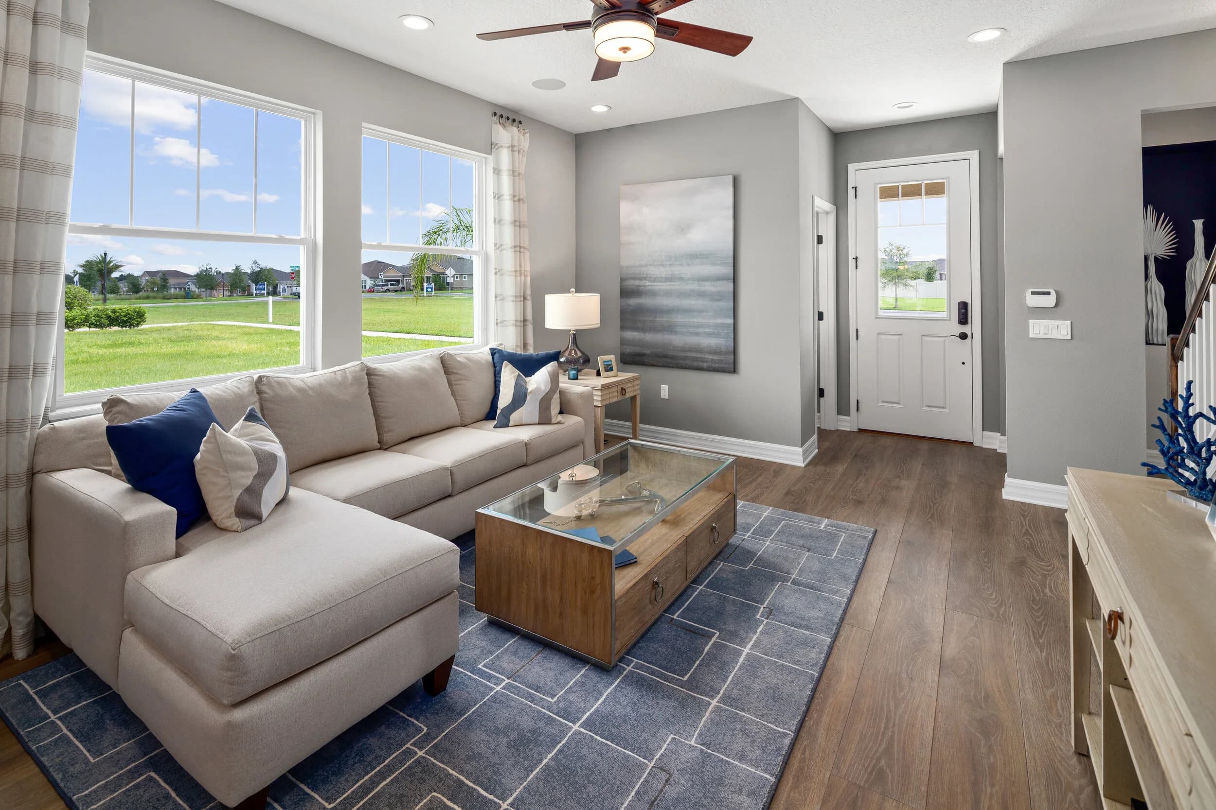 Staged model living room with navy pillows and glass coffee table