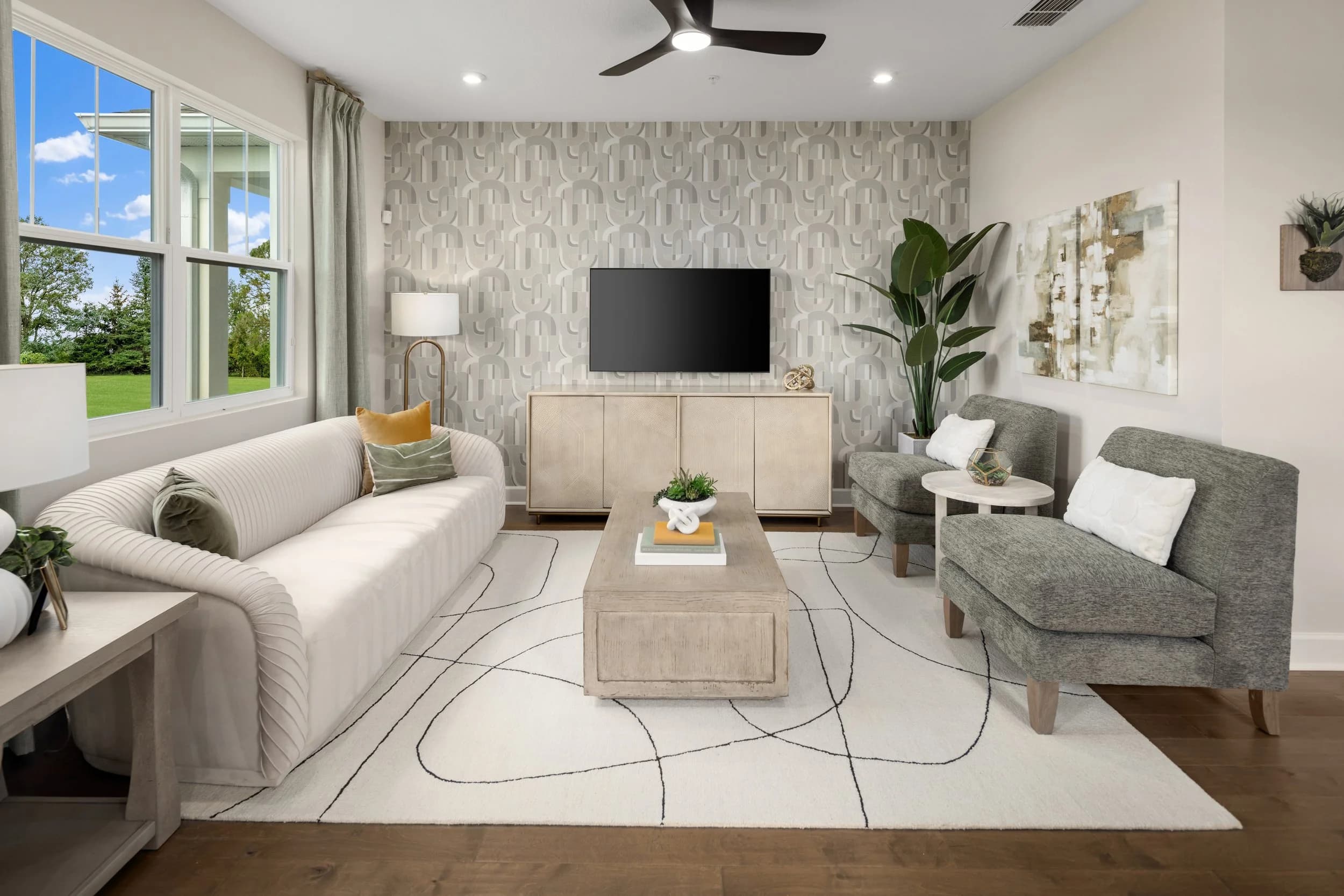 Living room with cream sofa, gray armchairs and a patterned wallpaper accent wall