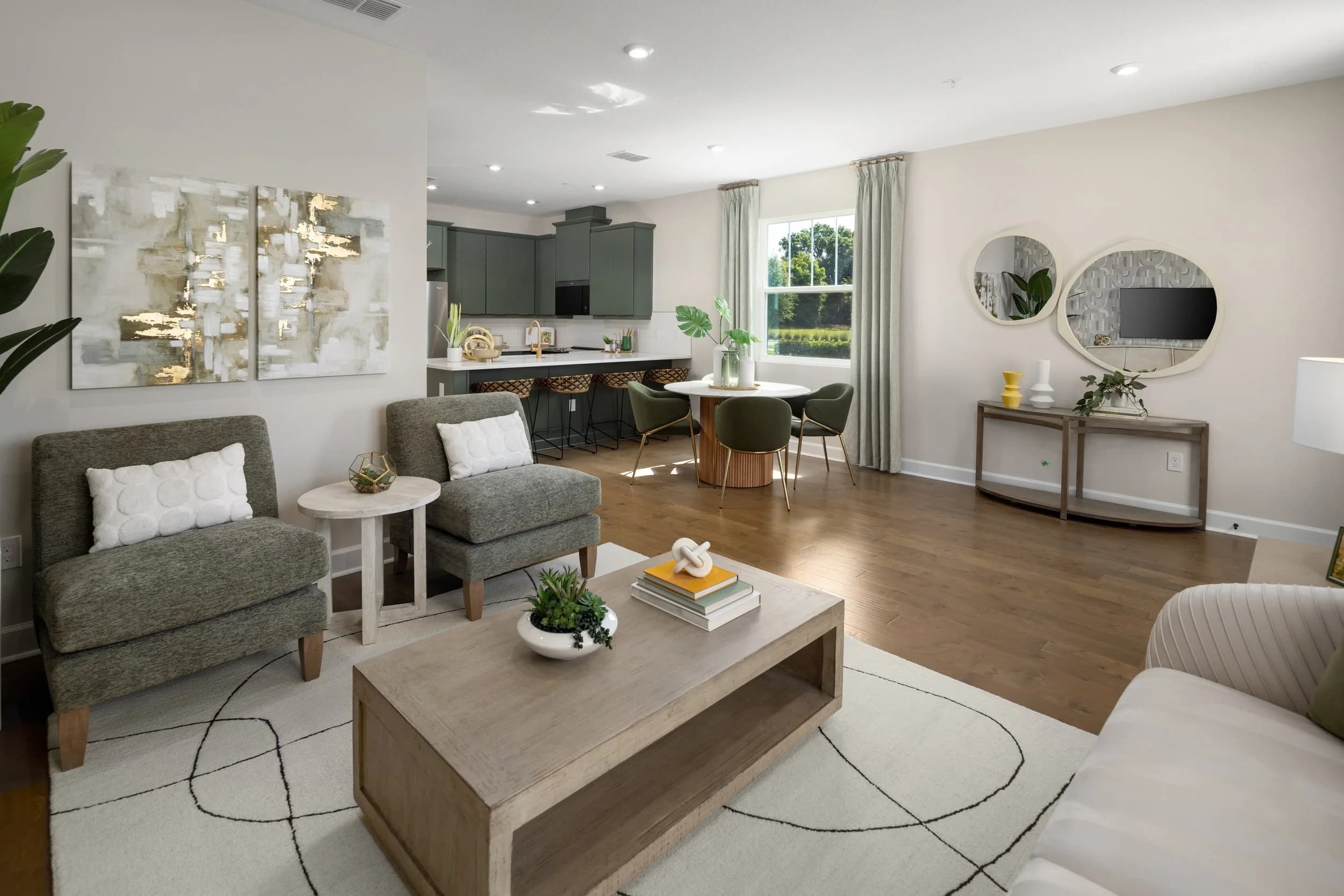 Living room looking toward the dining table and kitchen with round mirrors and gold art