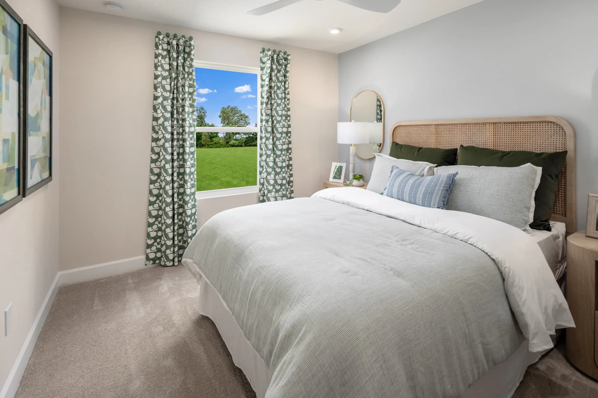 Primary bedroom with cane headboard, green patterned curtains and layered bedding