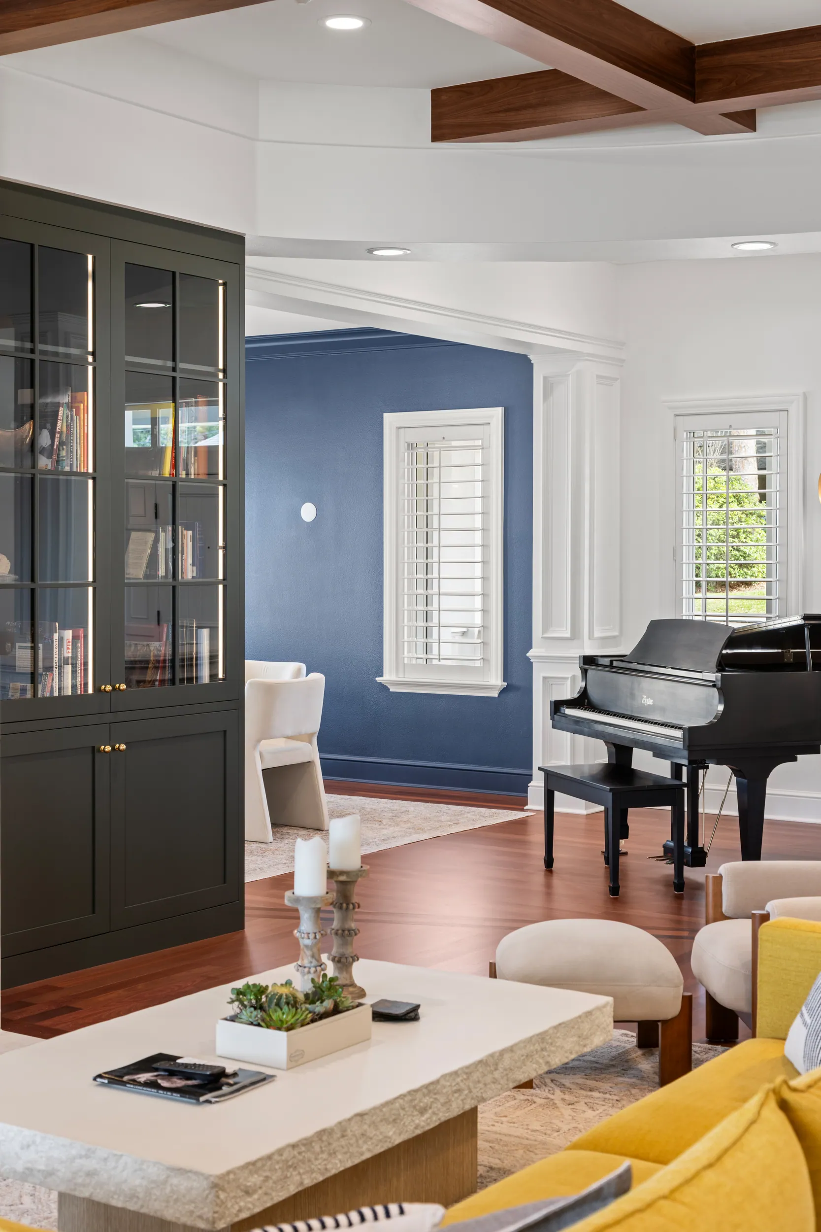 Study with navy walls, glass-front bookcases and a baby grand piano