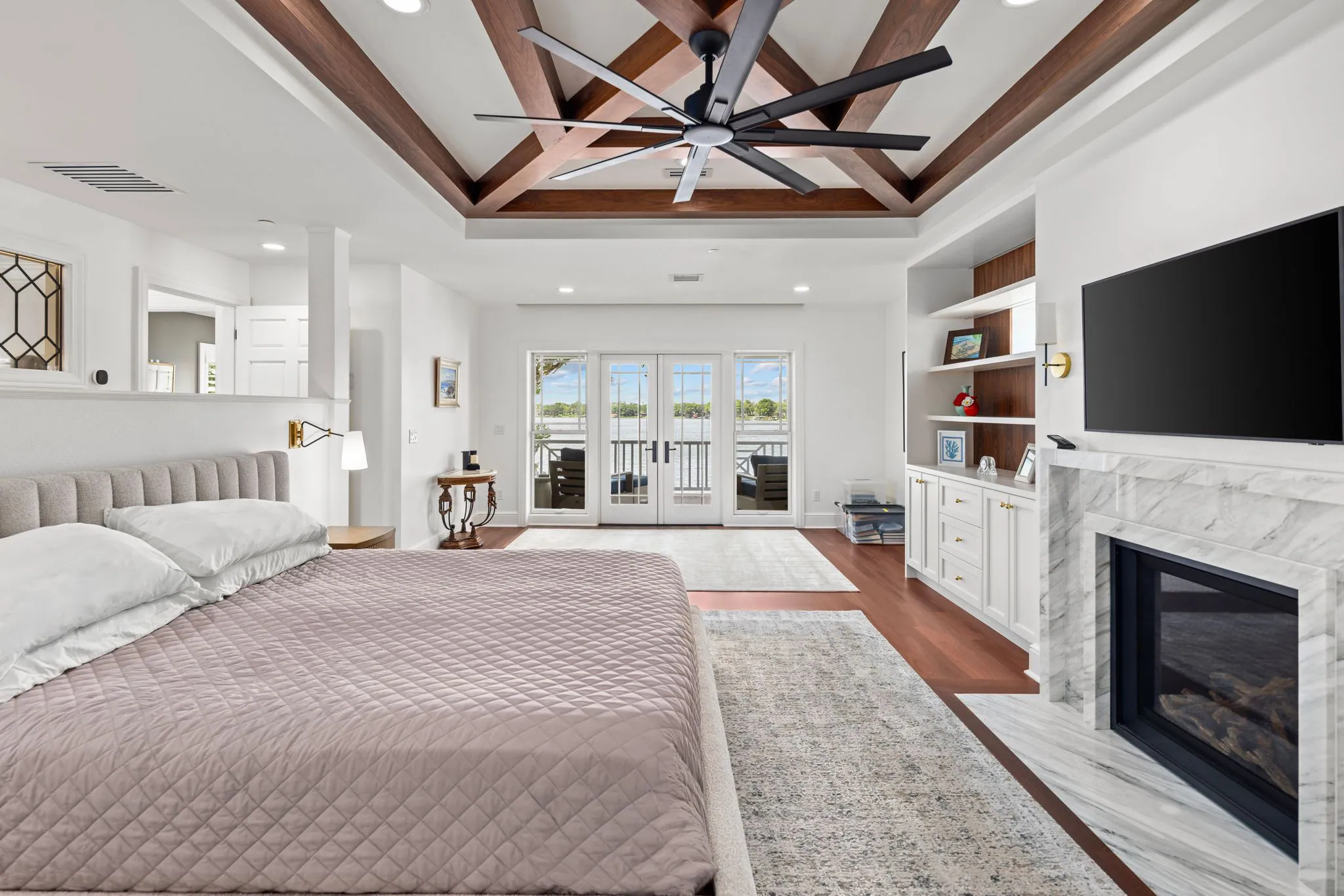Primary bedroom with beamed ceiling, fireplace and French doors to the porch