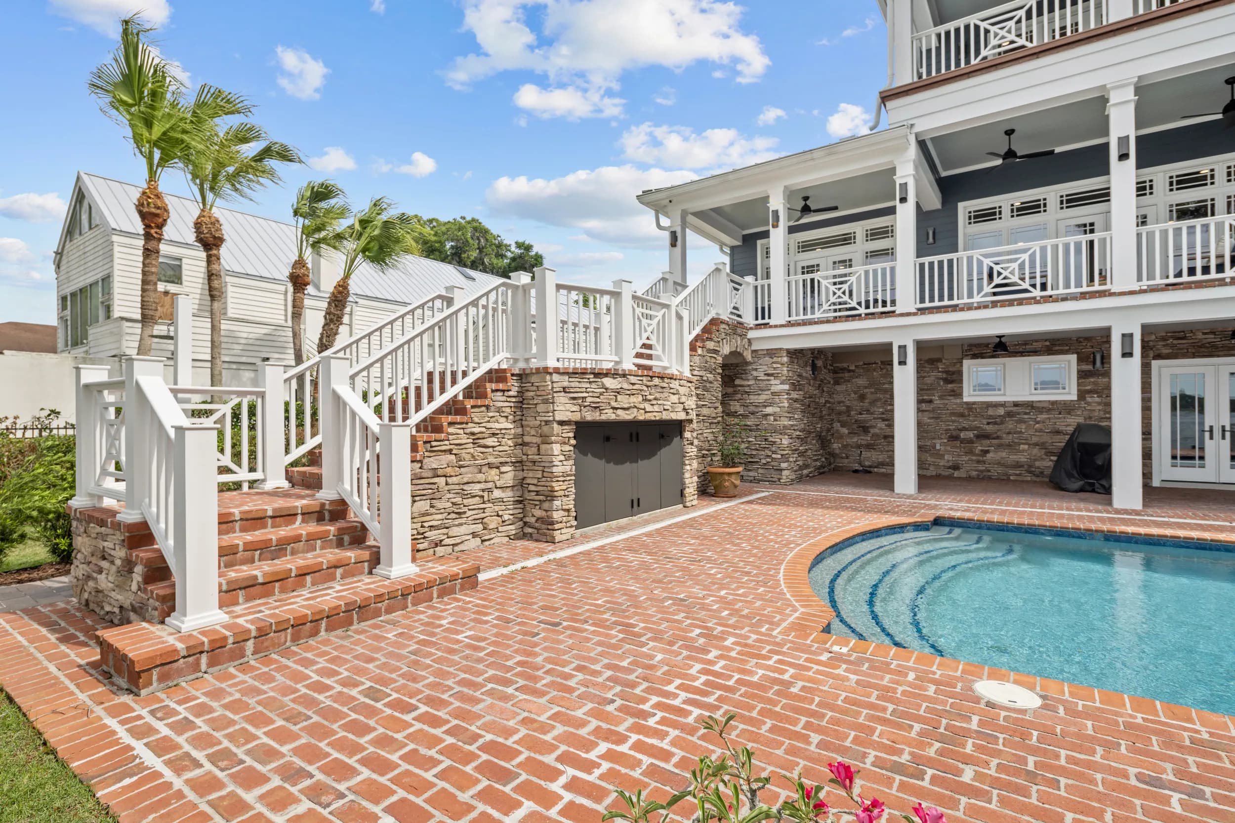 Pool terrace with stairs up to the covered porch and outdoor kitchen