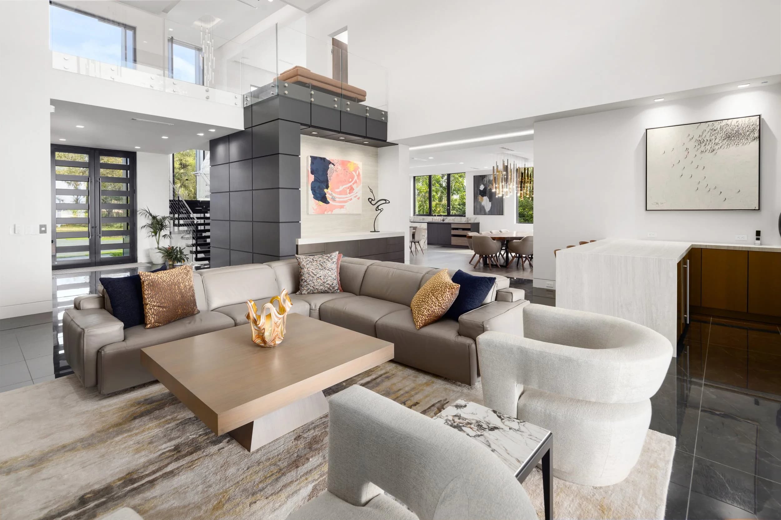 Great room with taupe sectional and loft balcony above, looking toward the dining area