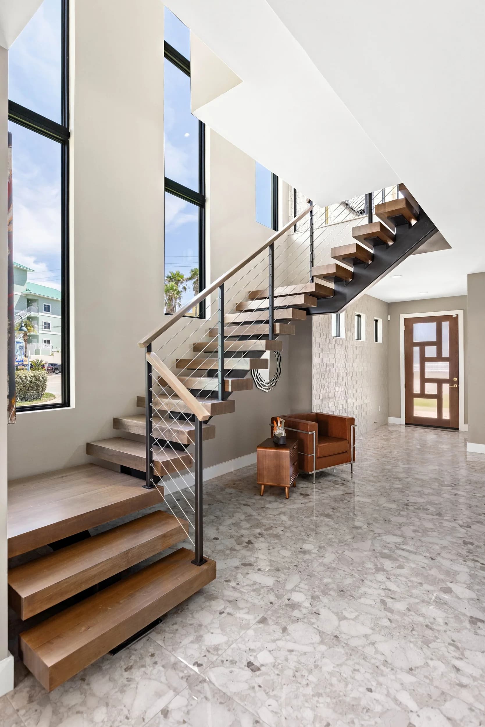 Vertical view of the open wood staircase with cable railing in the two-story entry