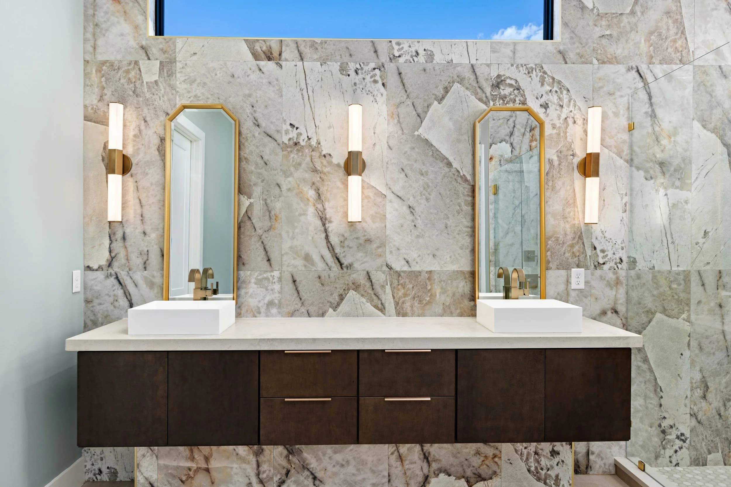 Primary bath with floating double vanity, vessel sinks and stone slab wall
