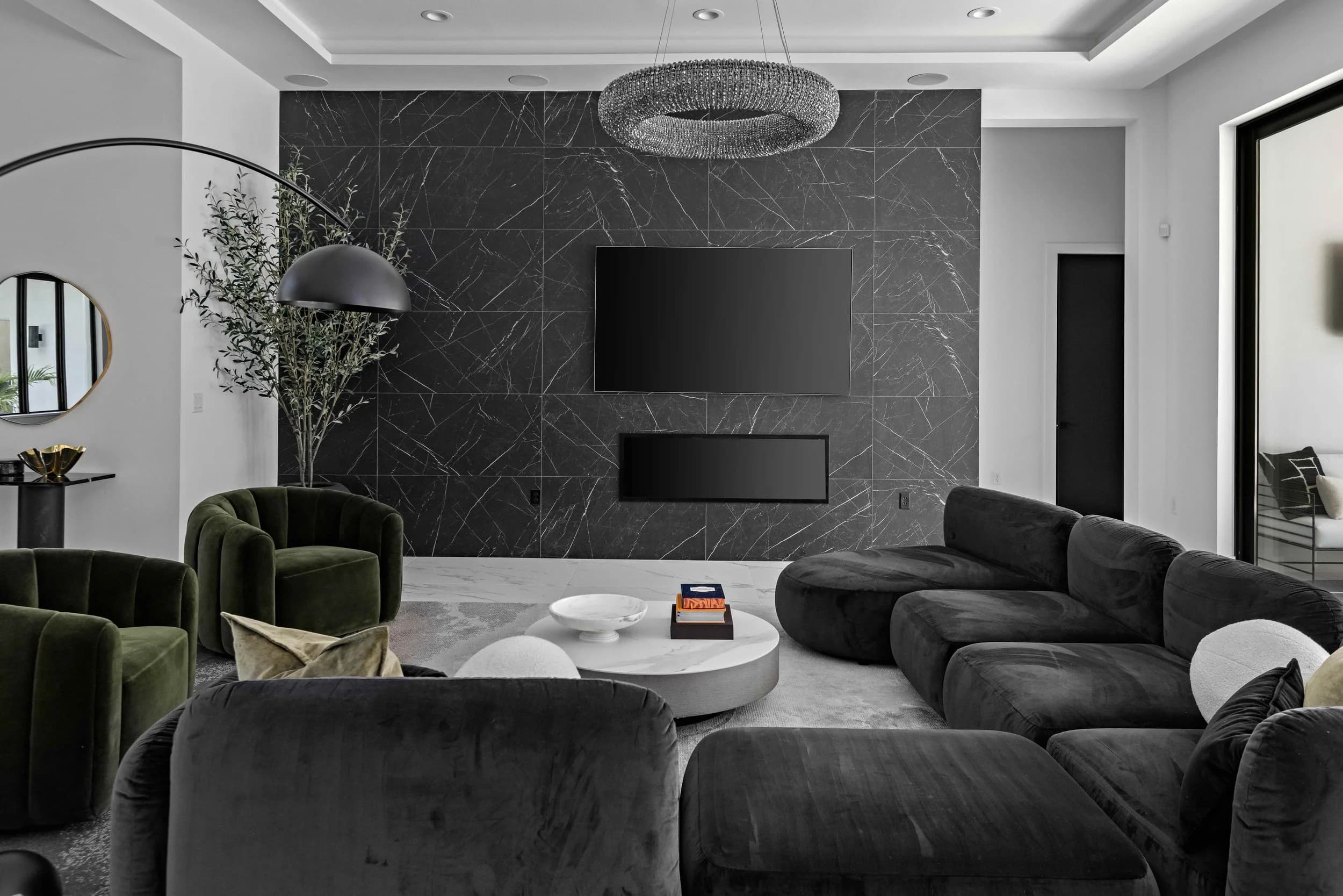 Close view of the great room seating with green velvet chairs and black sectional