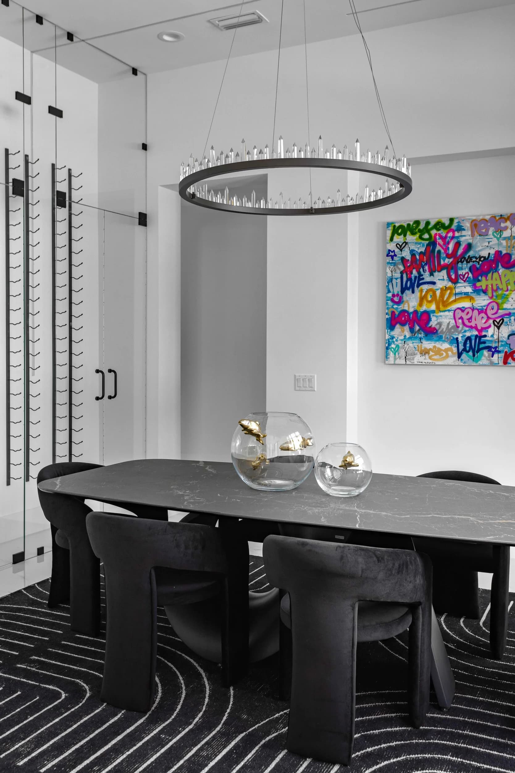 Vertical view of the dining room with black table, ring chandelier and graffiti art