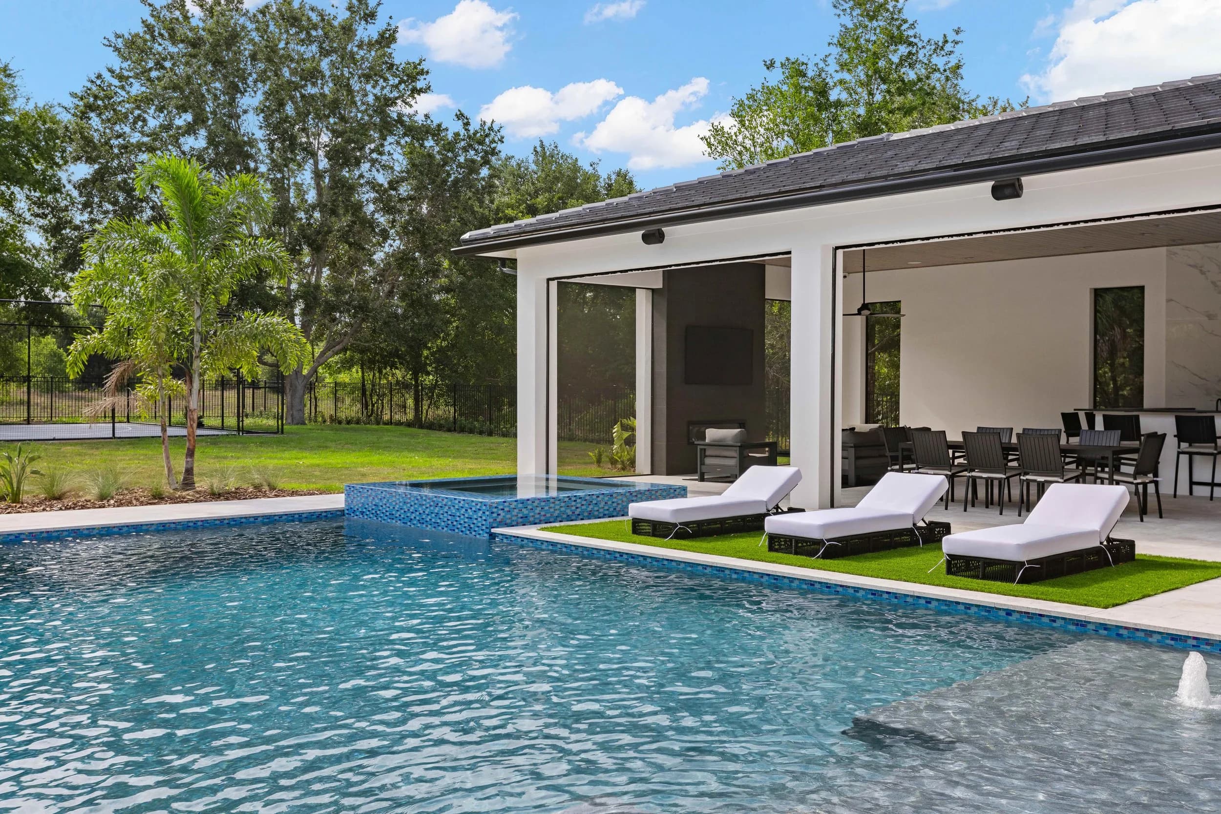 Pool by day with sun shelf, loungers and covered lanai with outdoor dining