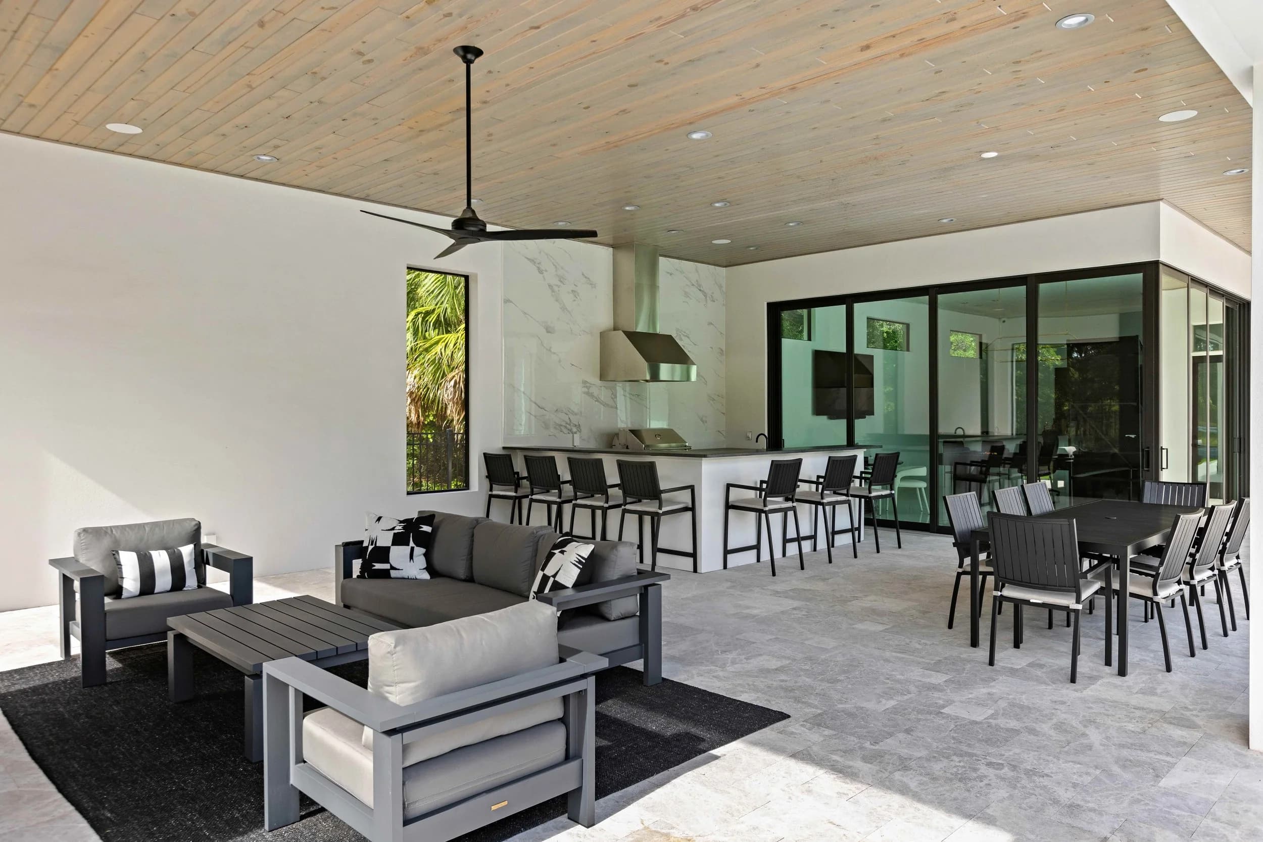 Covered lanai with outdoor kitchen, bar stools, dining set and lounge seating
