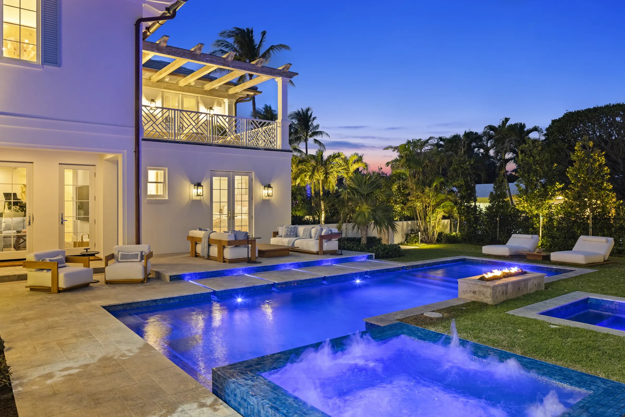 Palm Beach house at twilight with lit pool, spa and rear terrace