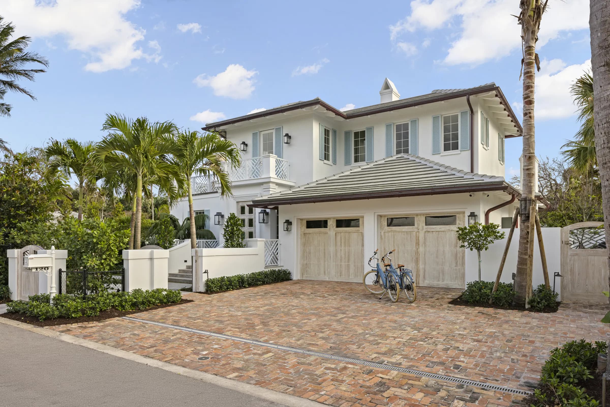 White two-story Palm Beach house with paver motor court and two-car garage