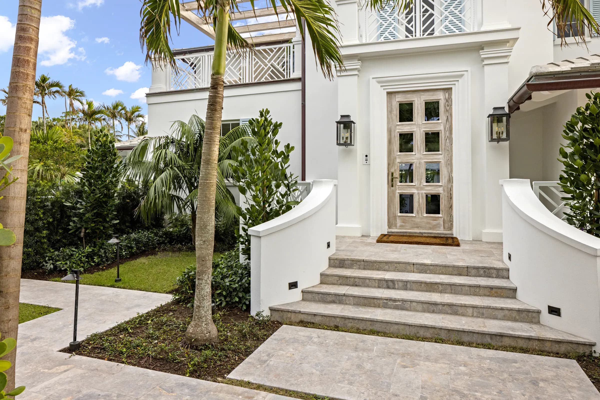 Curved entry steps up to a carved wood front door under a lantern