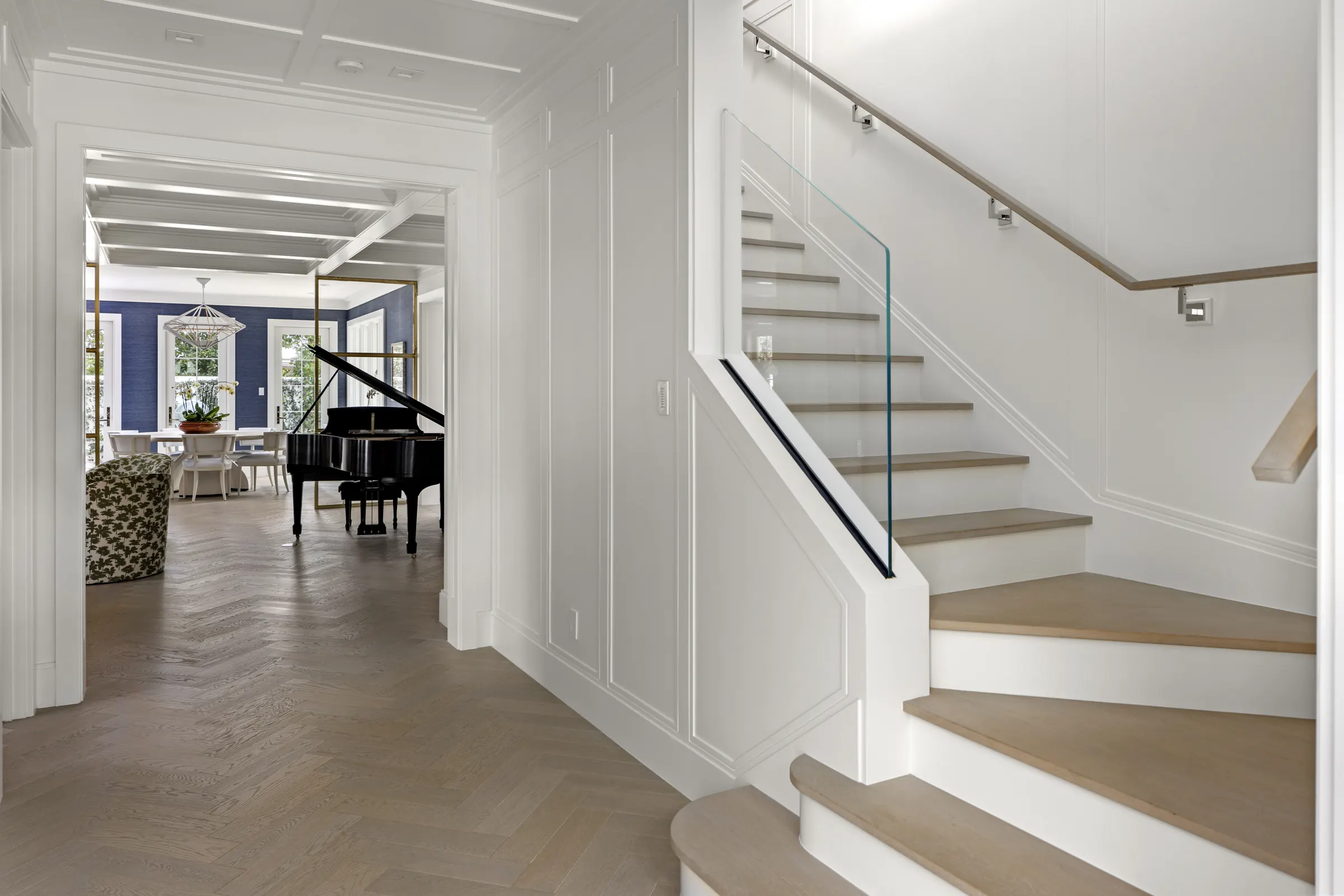 Foyer with herringbone floor, open stair and a grand piano beyond