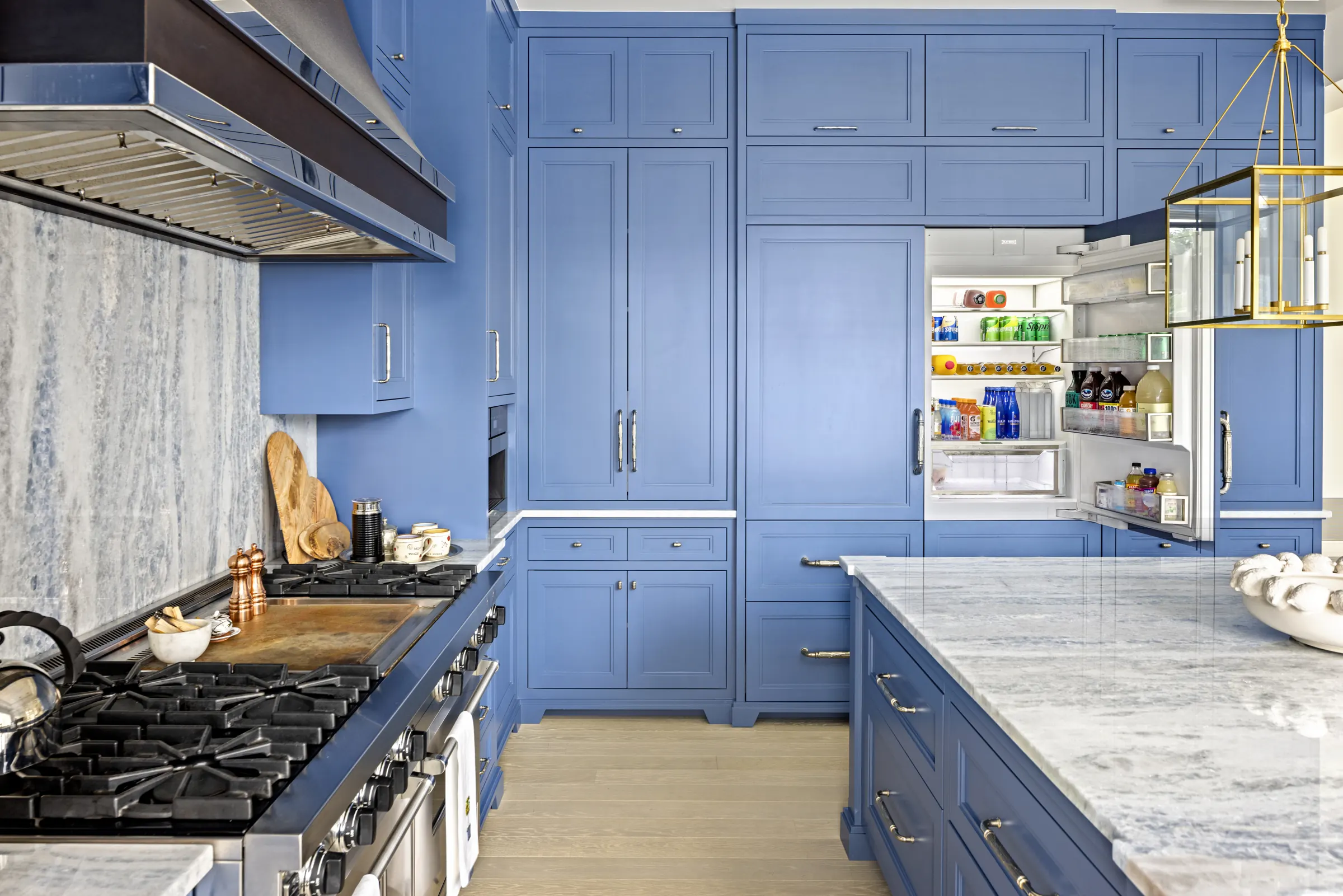 Blue kitchen with marble counters and a professional range