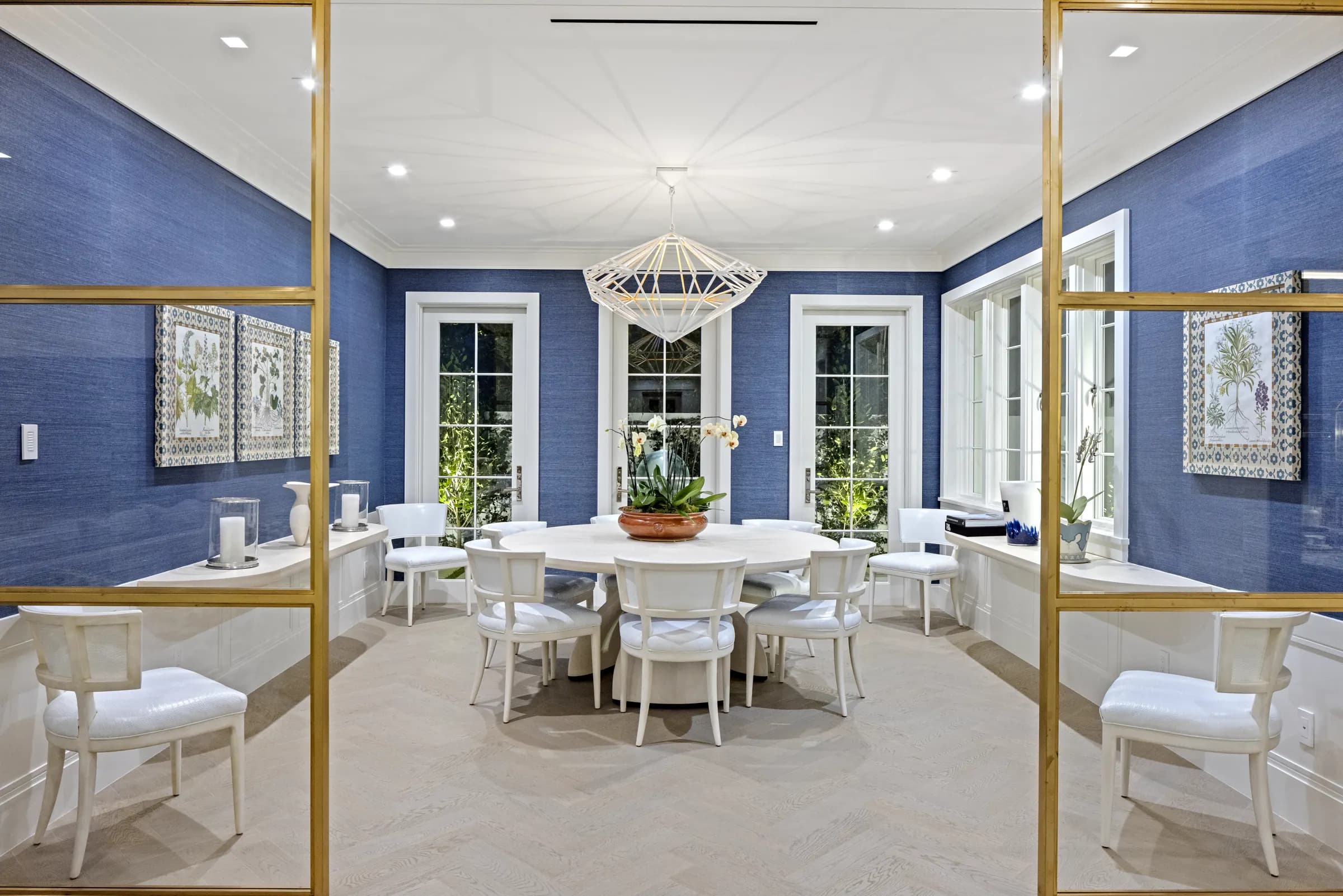 Blue-walled garden room with round dining table and brass doors