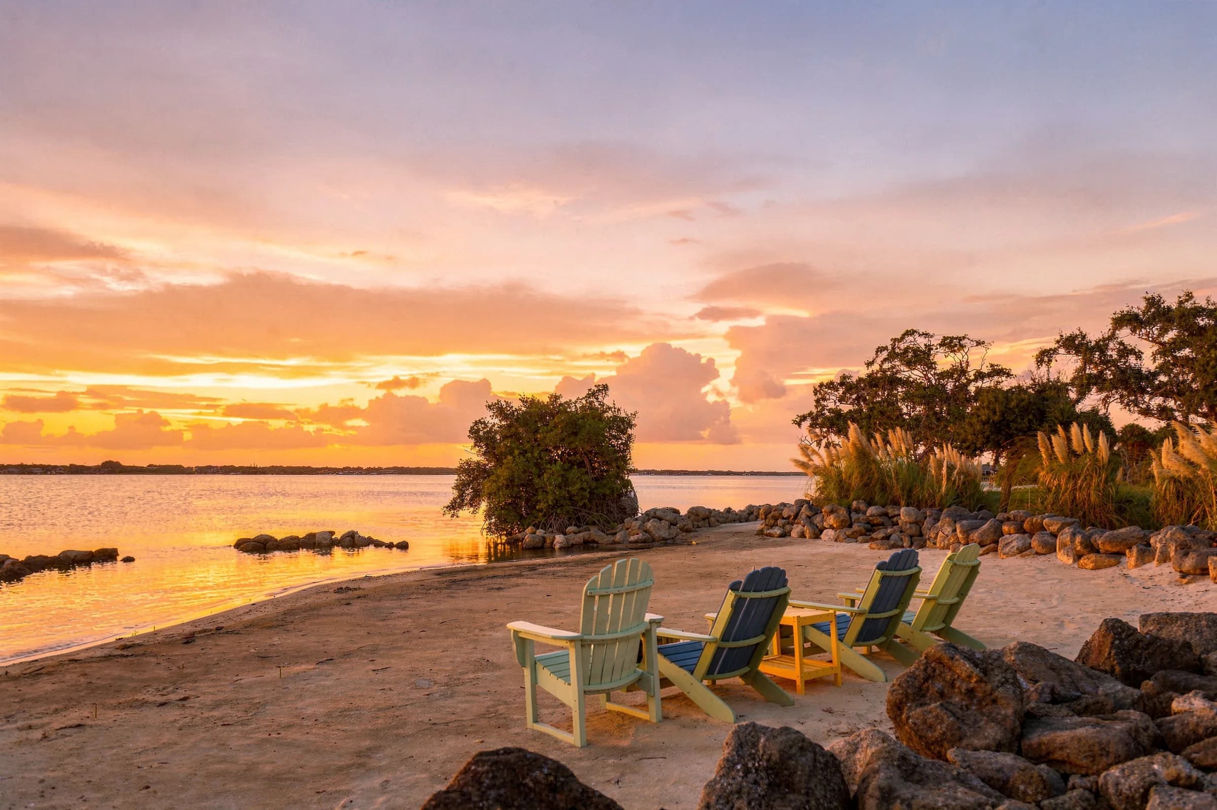 Private sandy beach with Adirondack chairs on the river at golden hour
