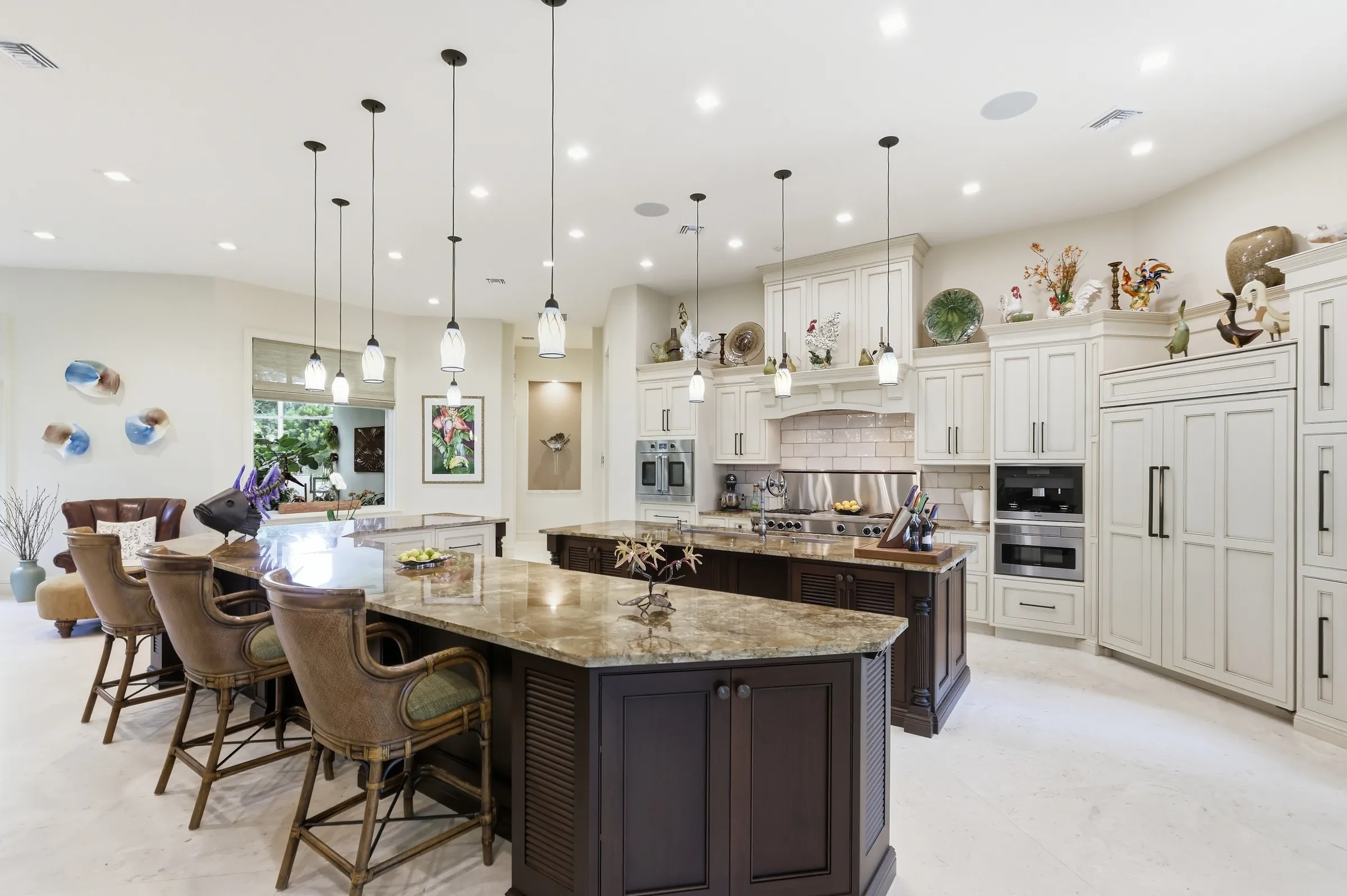 Kitchen with two granite islands, bar seating and a wall of pendants