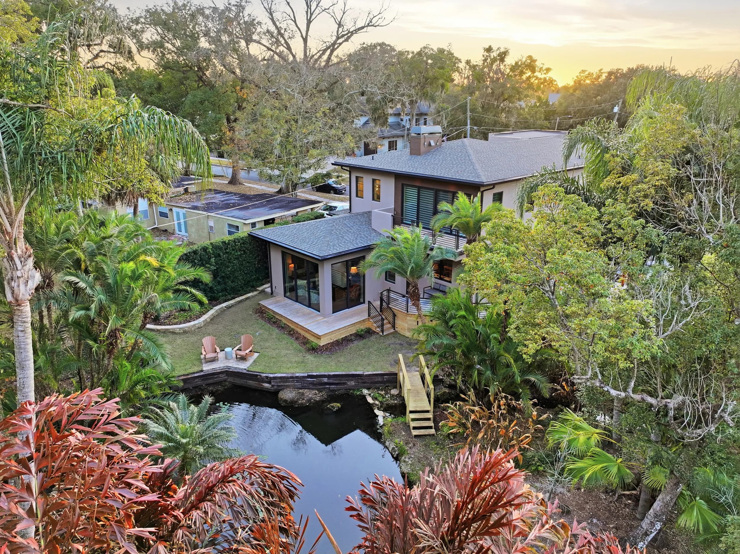 Aerial of a modern lakefront home at sunset with pool and dock on Lake Sue, Orlando