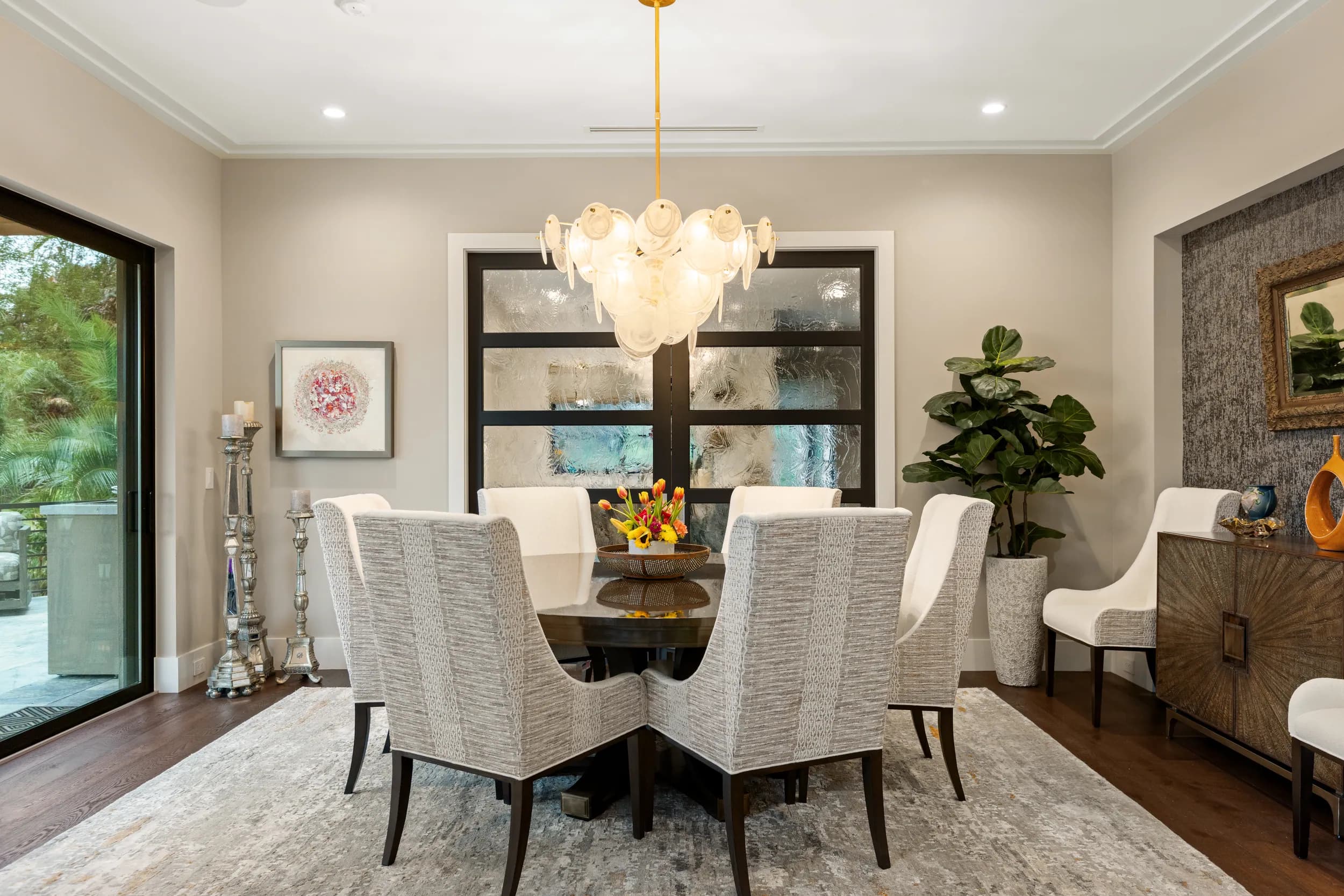 Dining room with round table, cream chairs and a tiered glass chandelier