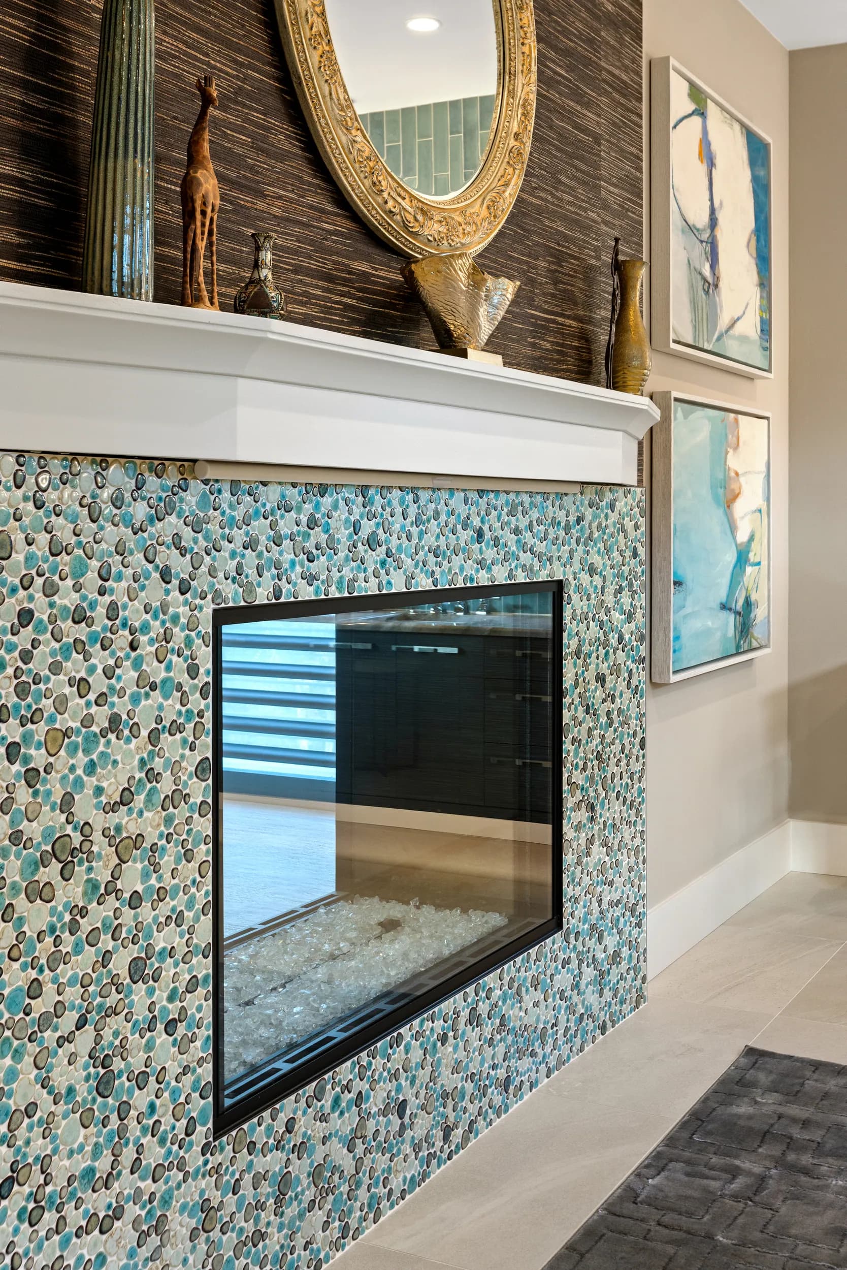 See-through fireplace framed in teal pebble mosaic tile