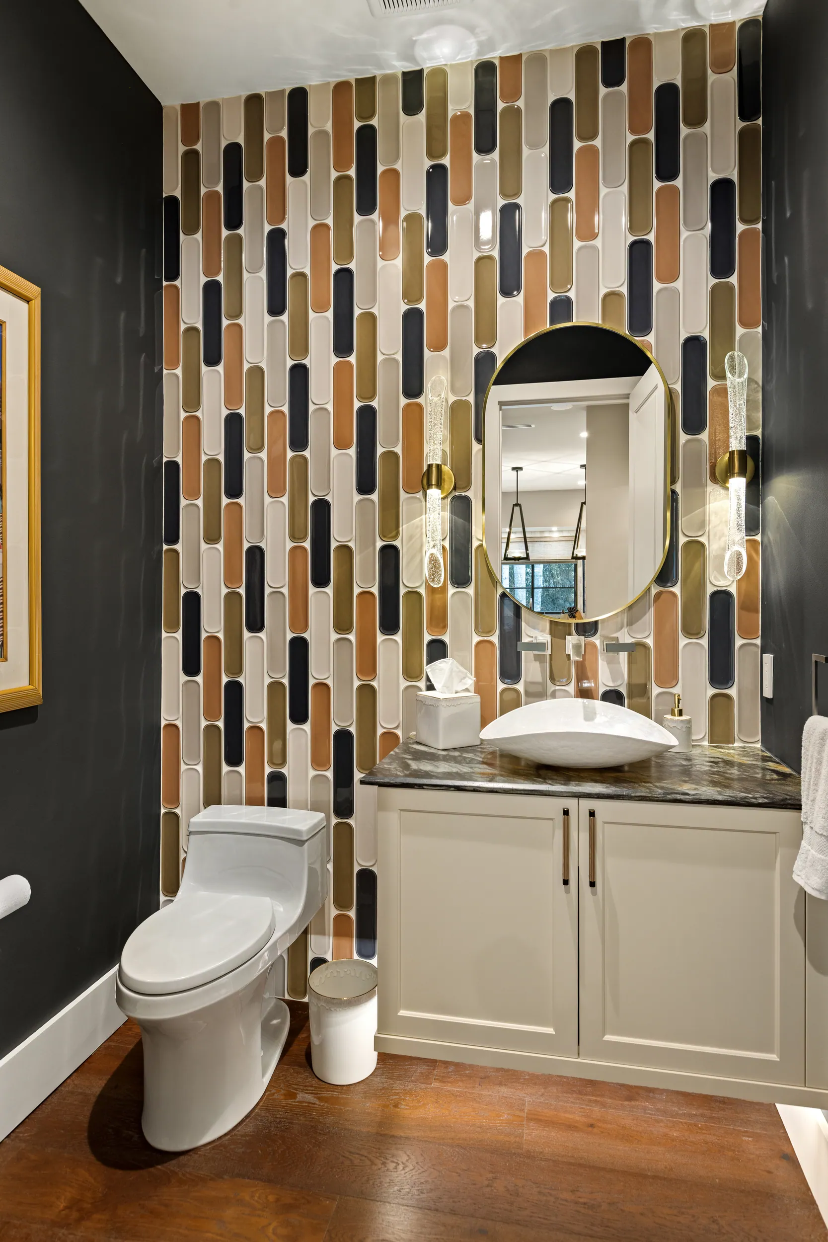 Powder bath with a vertical glass-tile wall, oval mirror and vessel sink